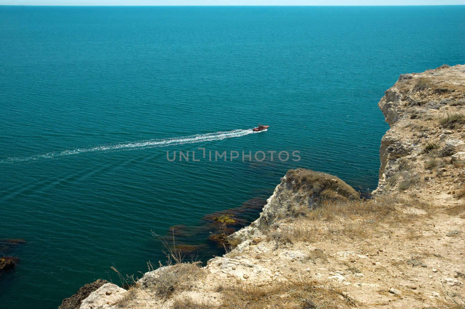 white inflatable motorized rubber boat is drifting over green-blue sea waves