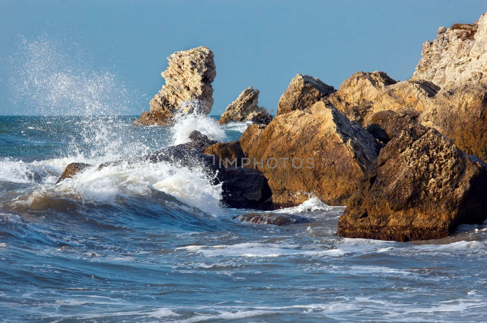 blue sea and rocks storming in light of sunset