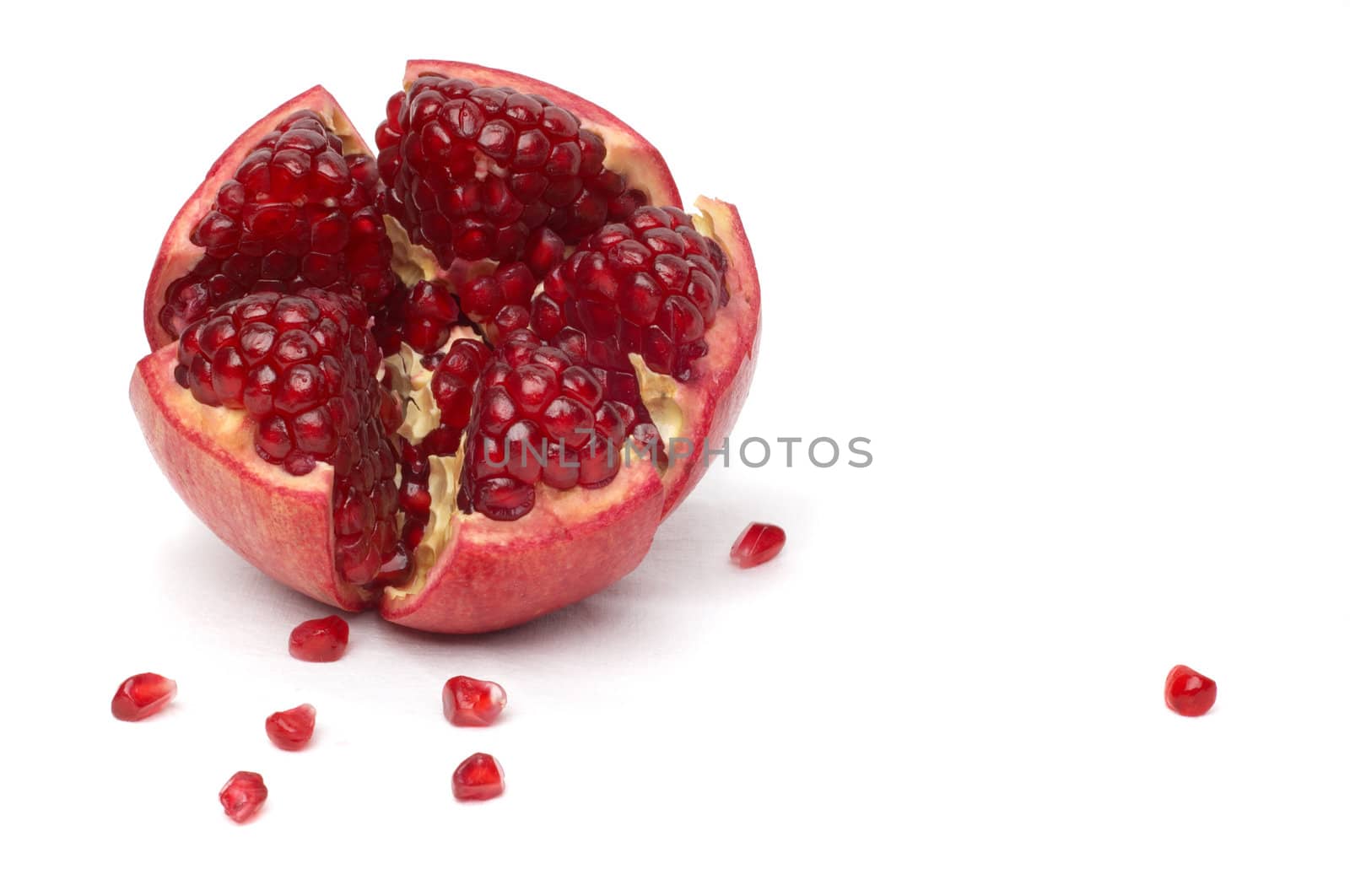 broken ripe pomegranate fruit and seeds over white cloth. isolated.