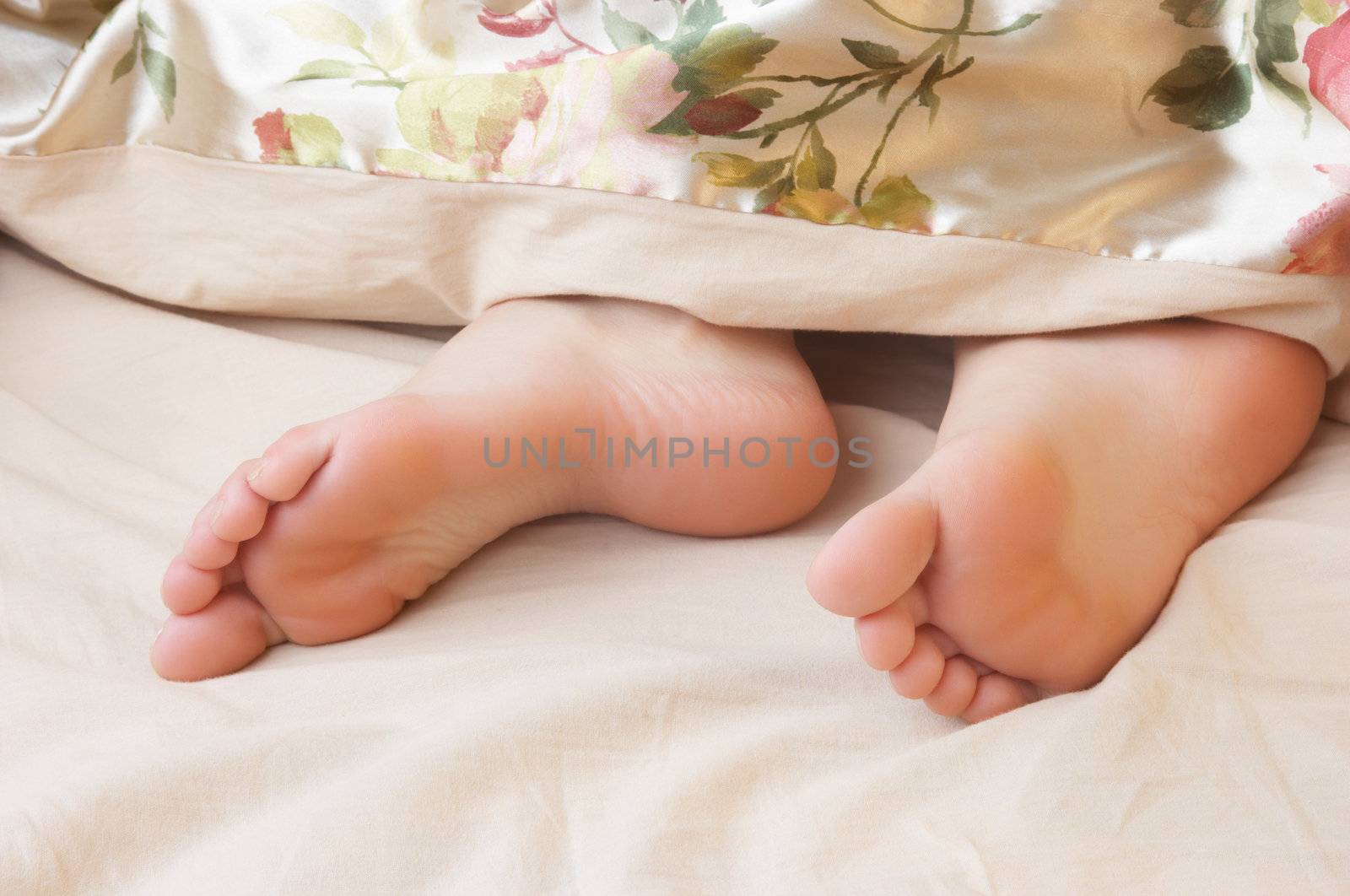 sleeping woman's cute feet, blanket over legs