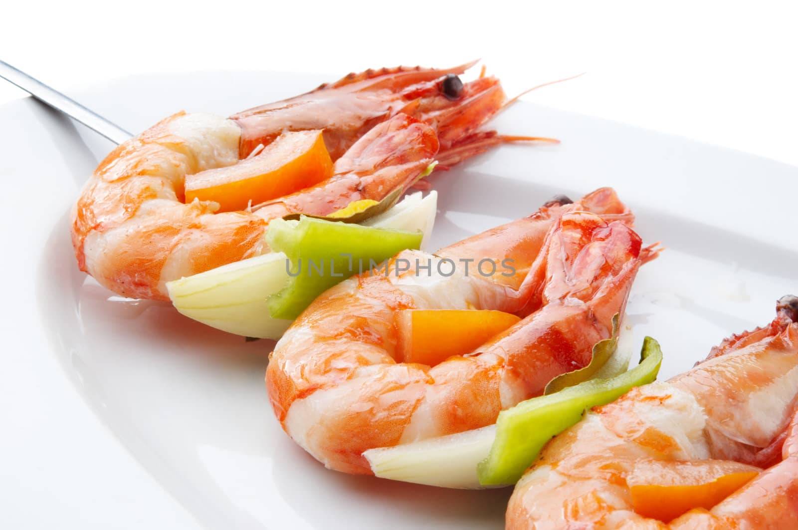 large juicy boiled shrimps served on skewer on plate