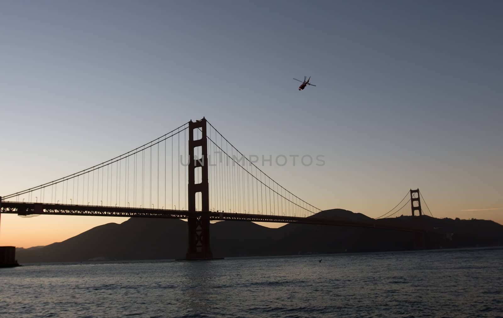 Helicopter over Golden Gate bridge at the dusk