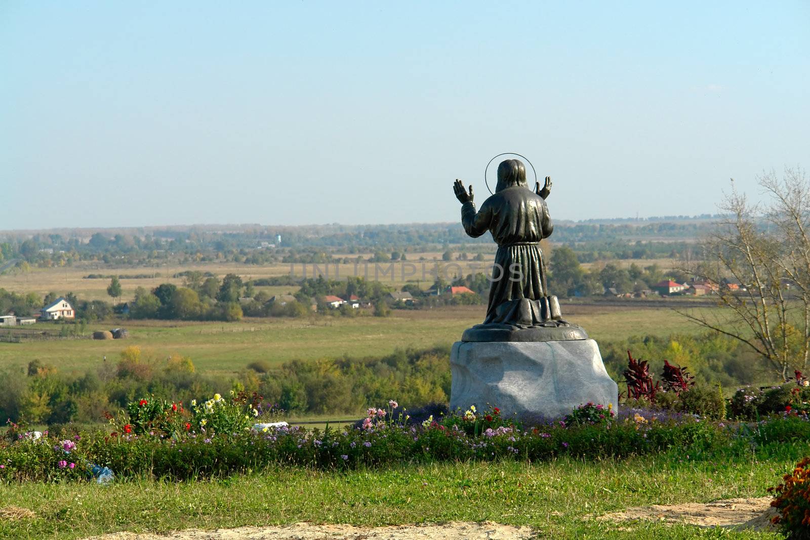 Statue of the eremite which prays on a hum noise of the blue sky                               