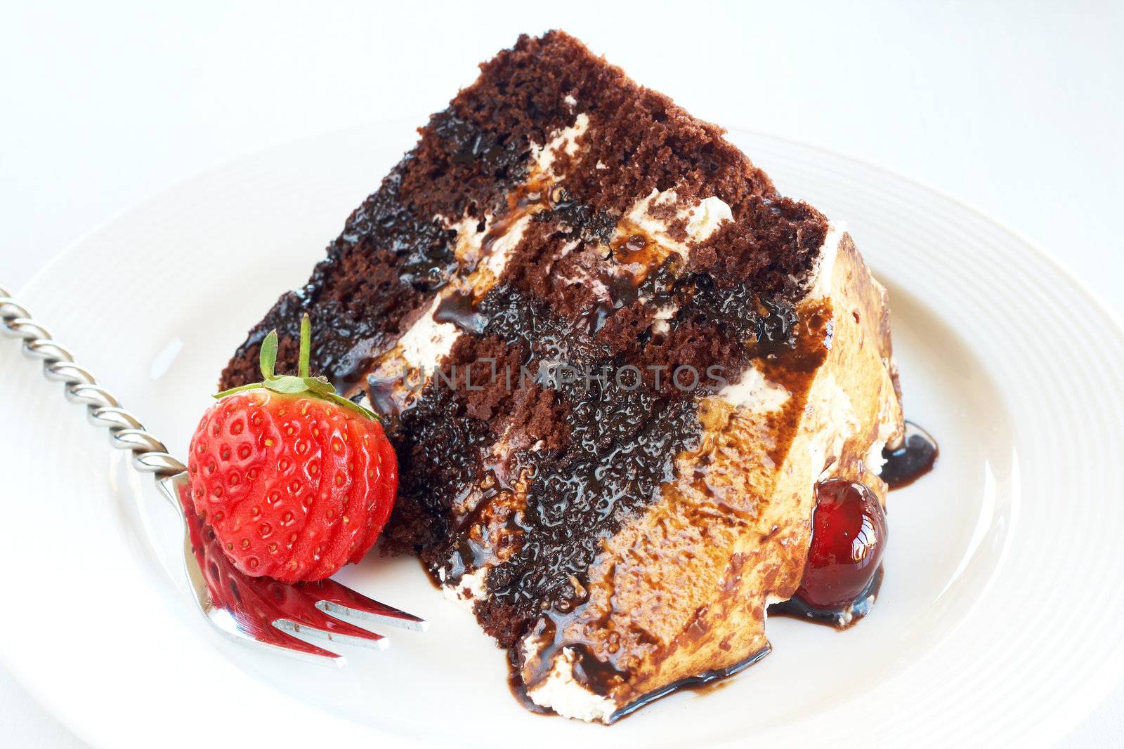 Slice of Black Forest cake with fresh cream and cherries, served on a white plate with silver fork