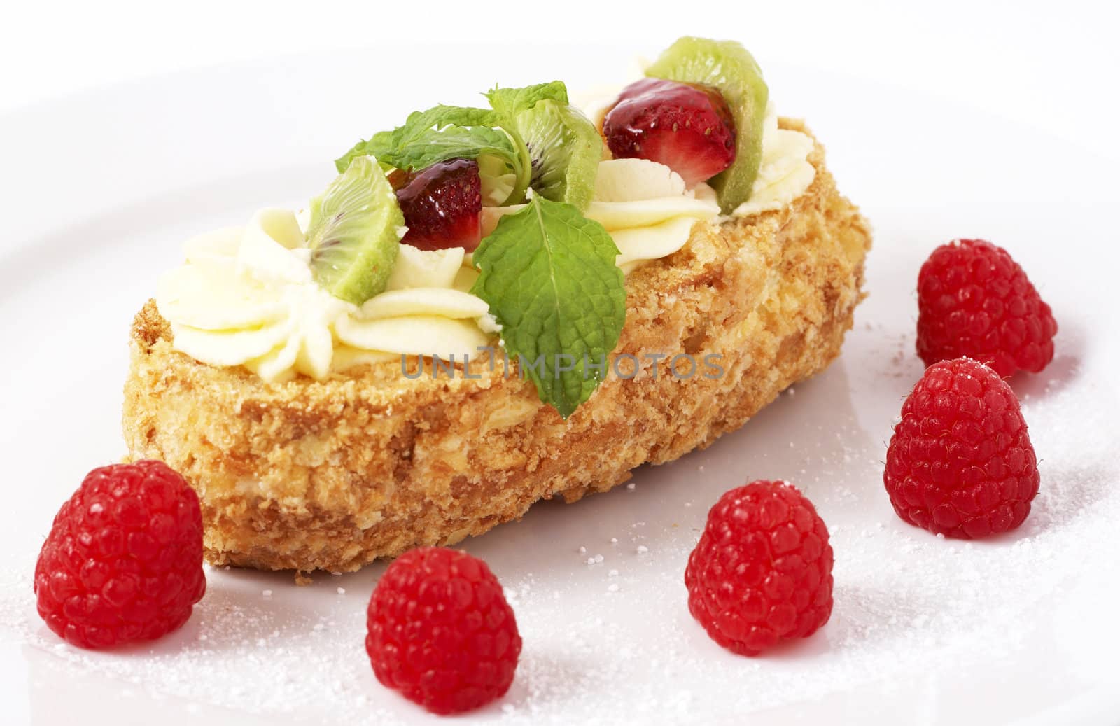 Fruit boat cake with kiwi, strawberries, and raspberries served on a white plate