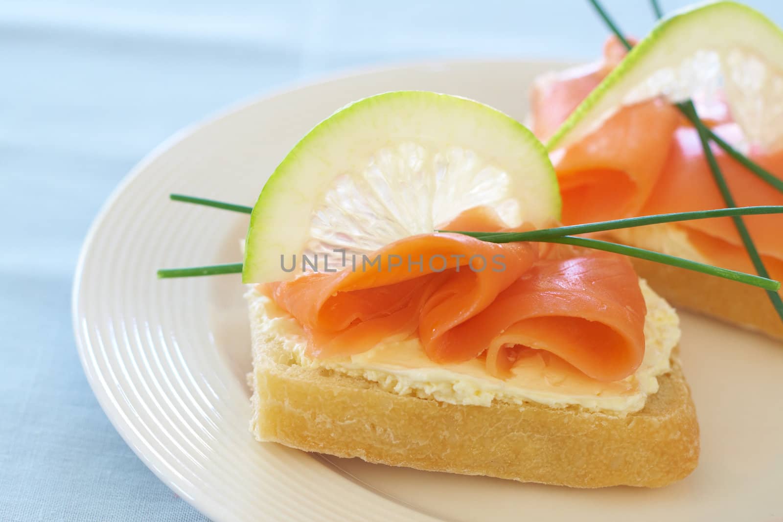 Smoked salmon and cream cheese on white bread with slice of lemon and chives