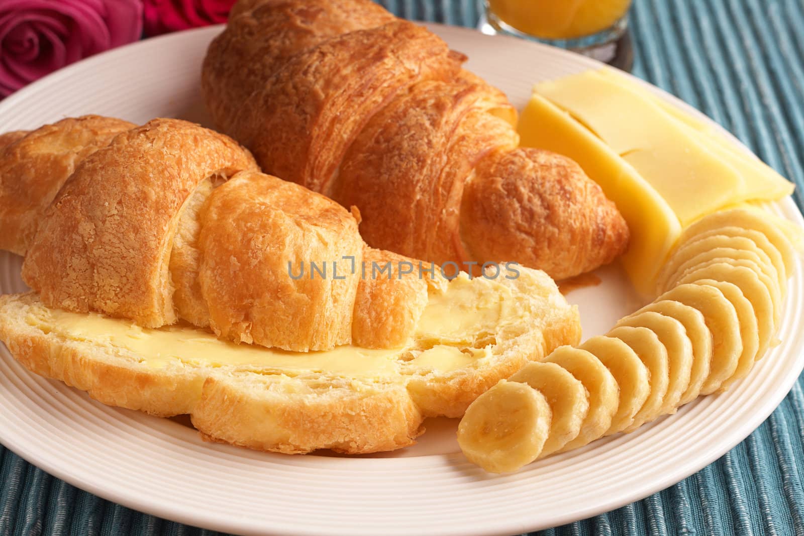 Breakfast plate with freshly baked croissants with butter, cheese and sliced bananas