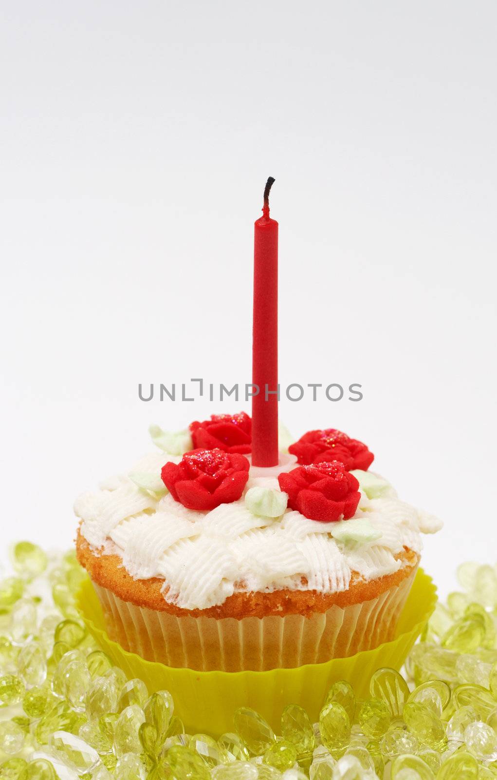 Fresh vanilla cupcake with basketweave buttercream icing and roses and birthday candle on white background