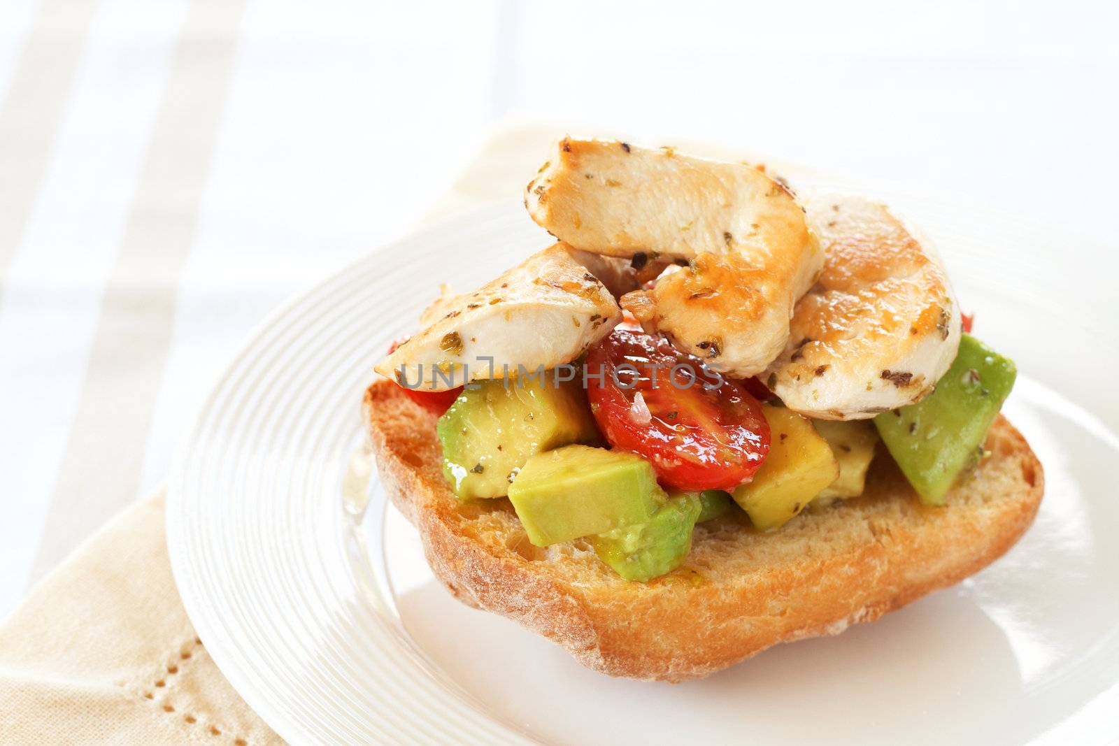 Tasty avocado, baby tomato and grilled chicken bruschetta on ciabatta bread