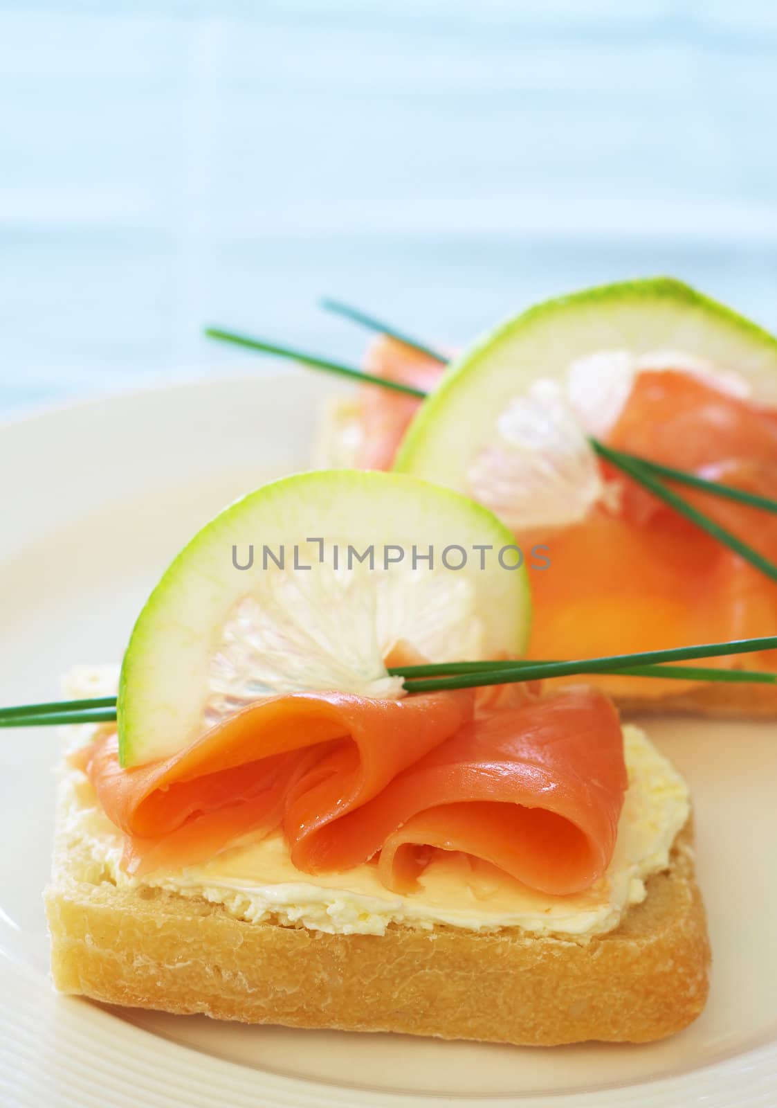 Smoked salmon and cream cheese starter on white bread with slice of lemon and chives