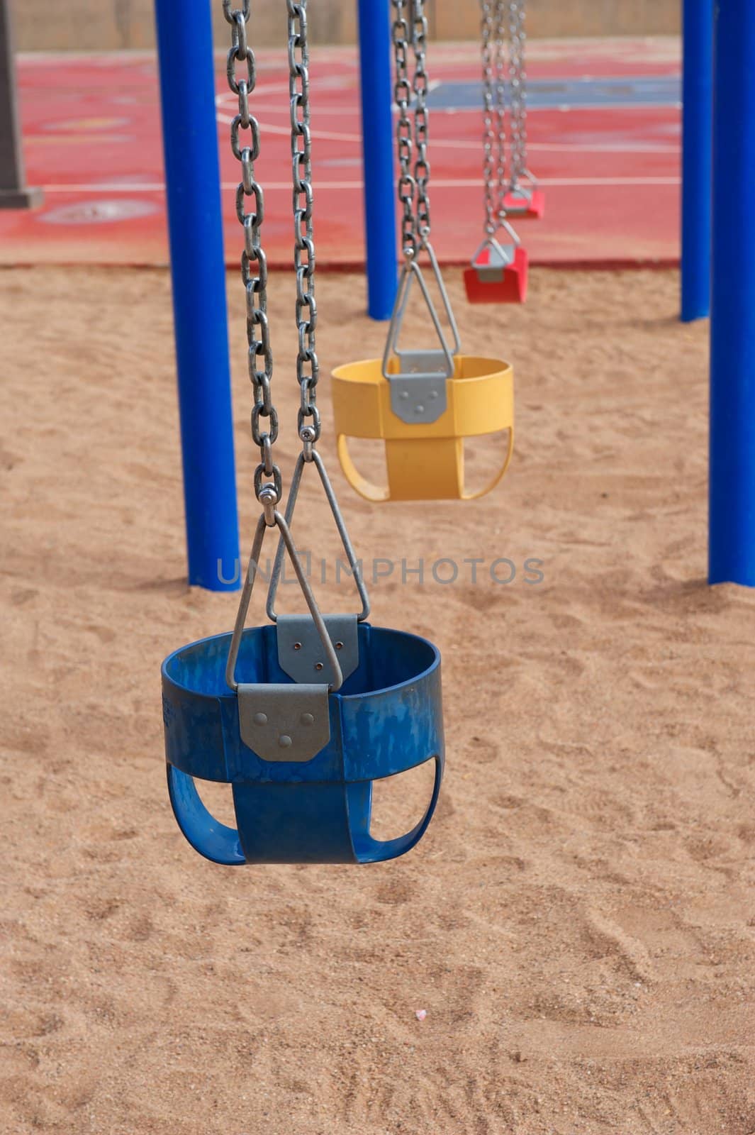 Colorful Empty Swings in Sand by pixelsnap