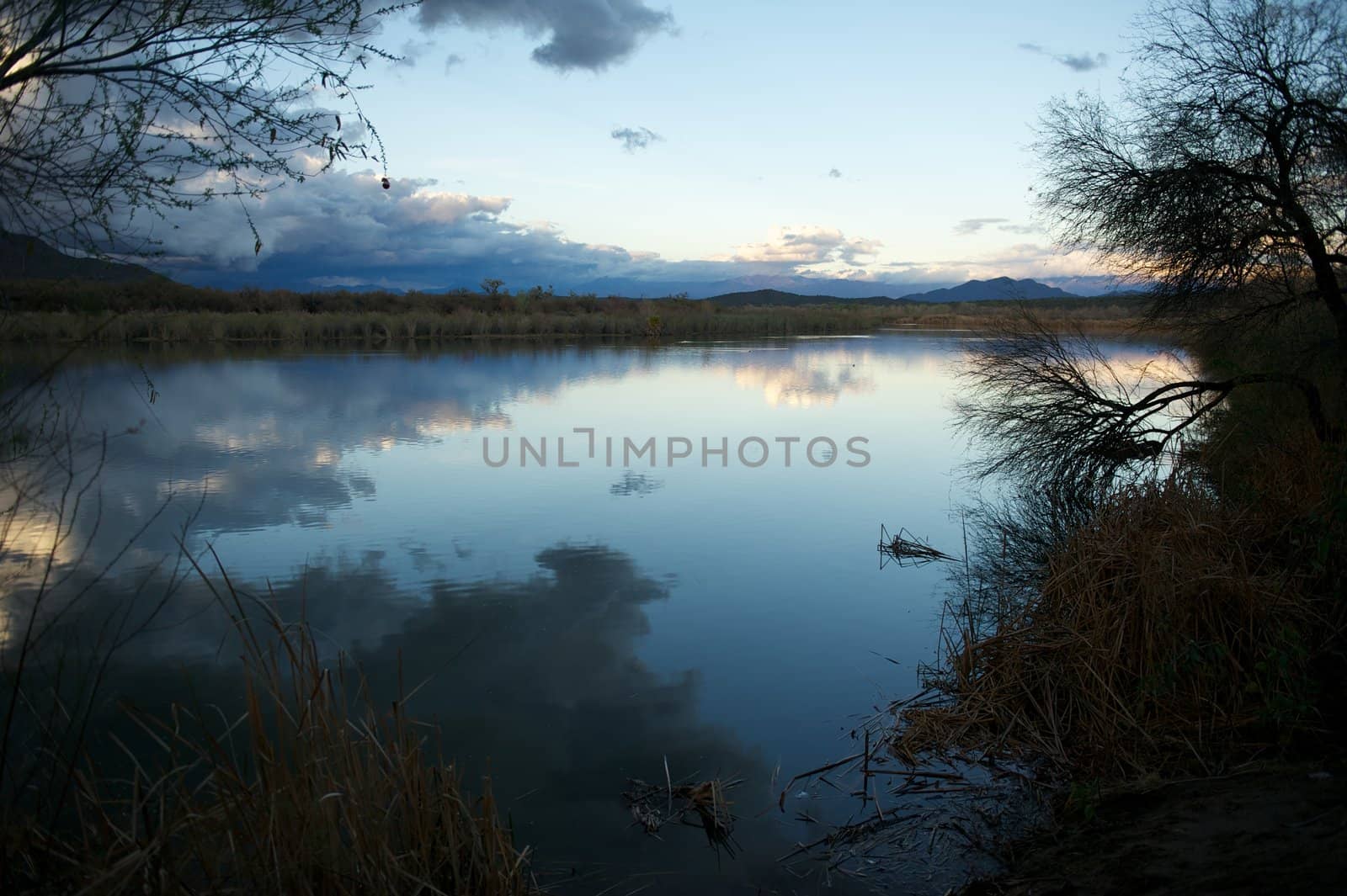 Calm river in the desert with mountain views and the reflections of white clouds