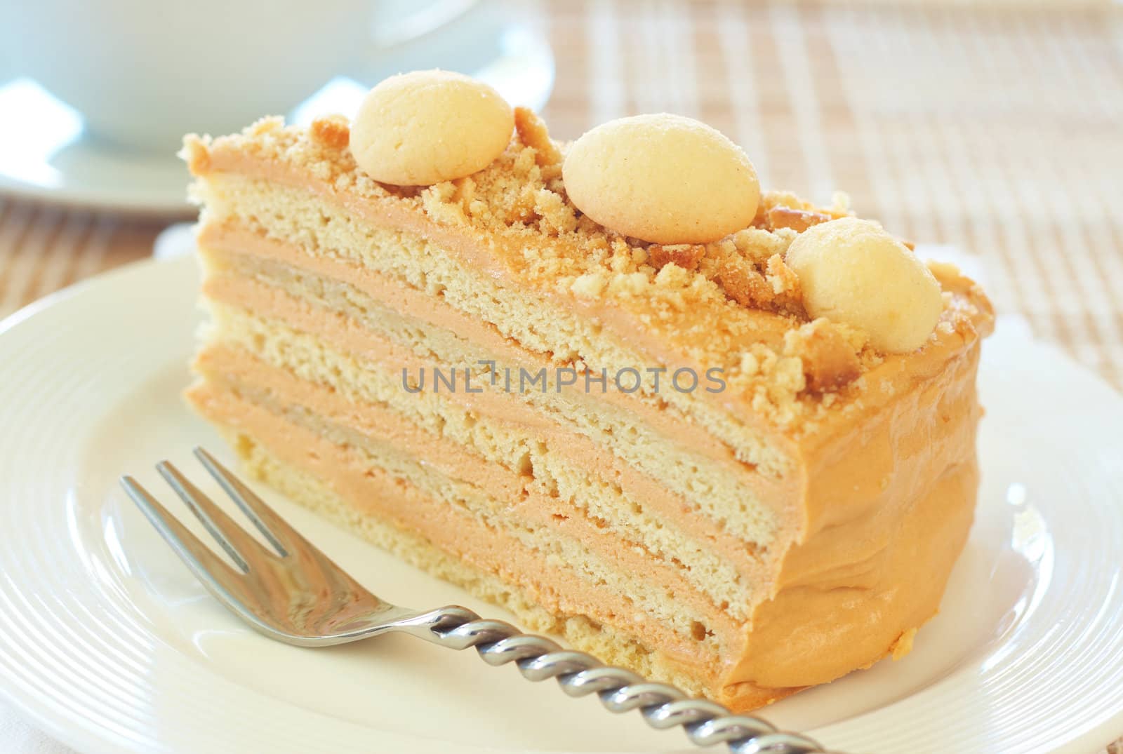 Caramel medovik cake made of honey and caramel cream, decorated with shortbread cookies on white plate