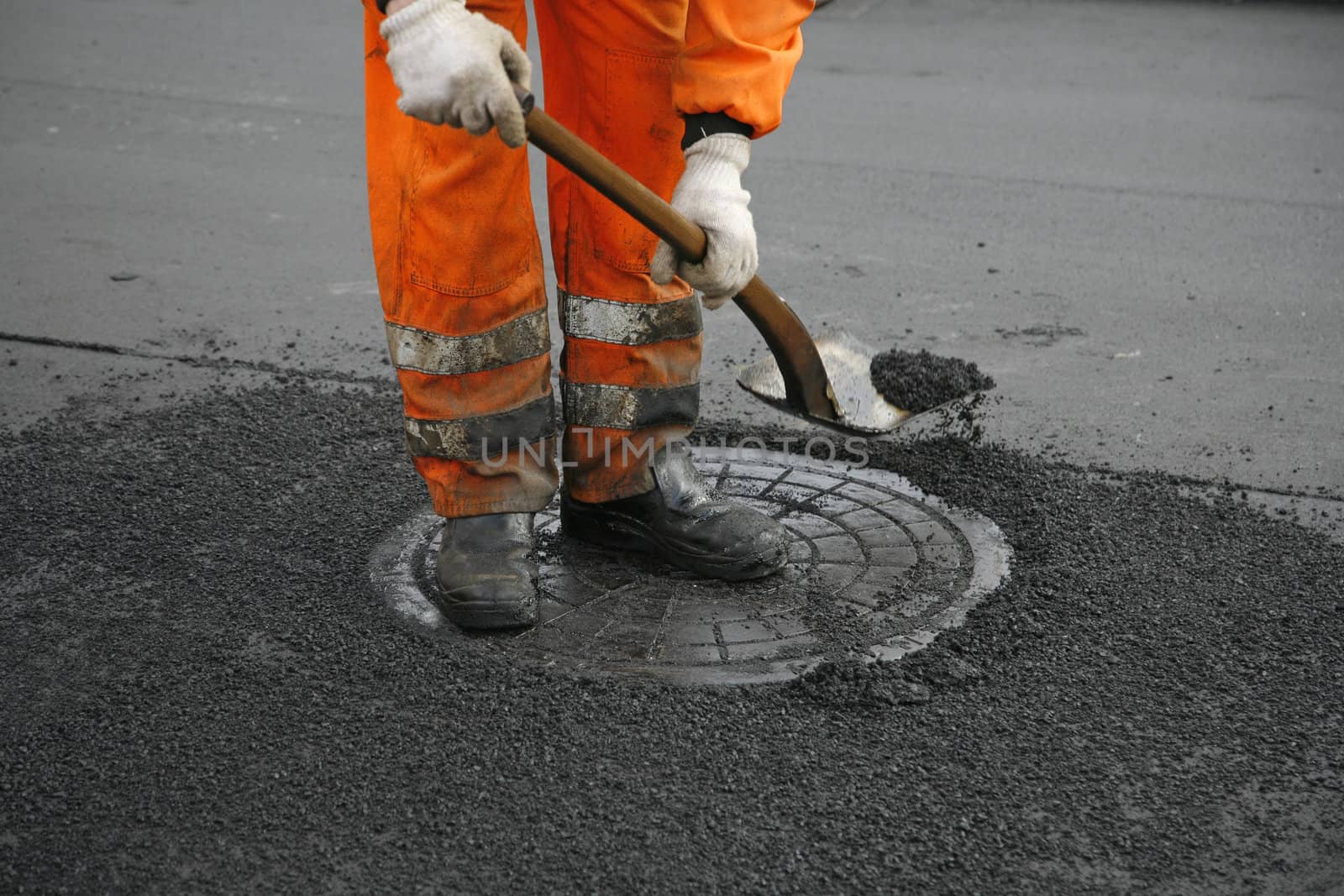 Asphalt worker by a manhole.