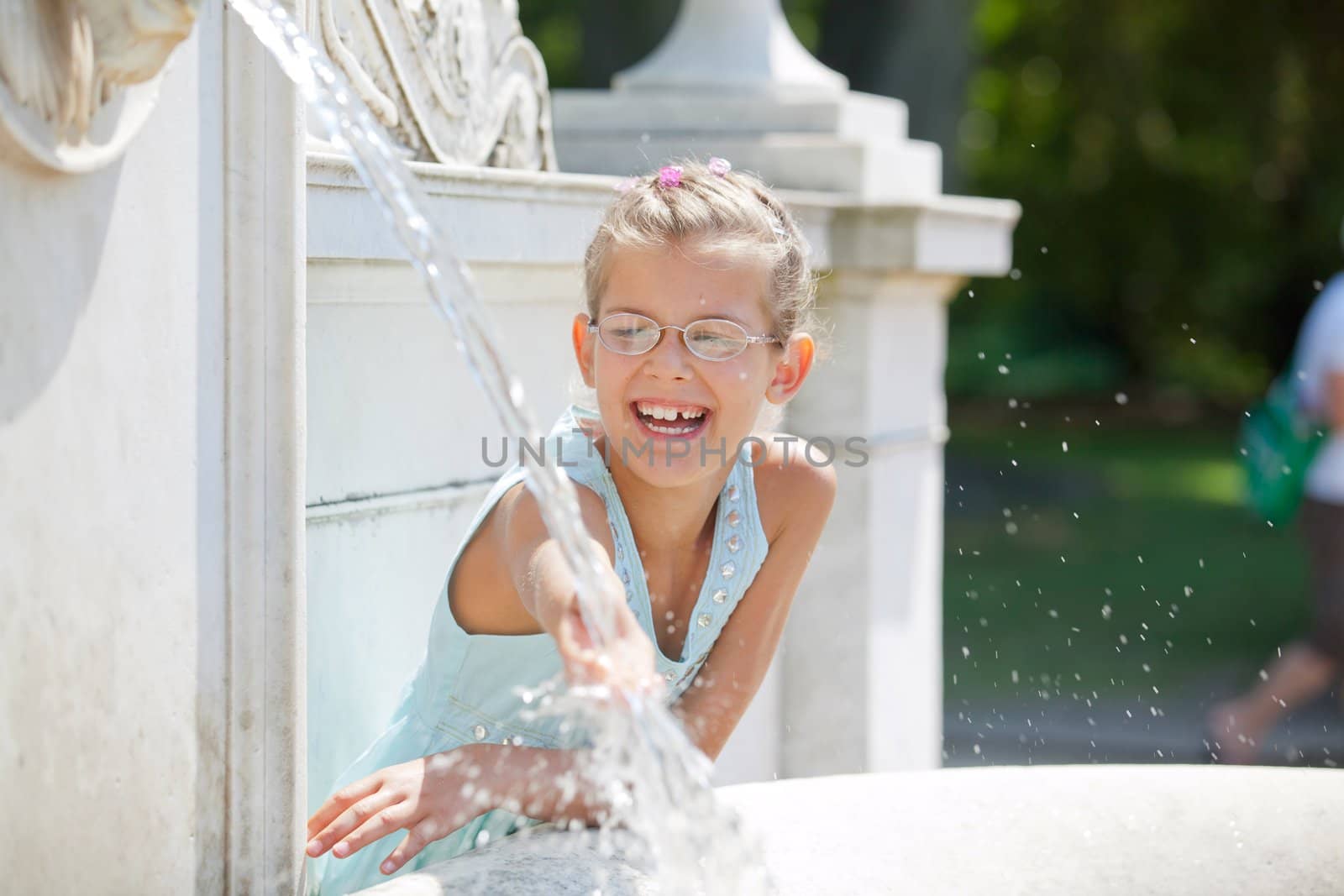 Beautiful girl playing with water in fountain