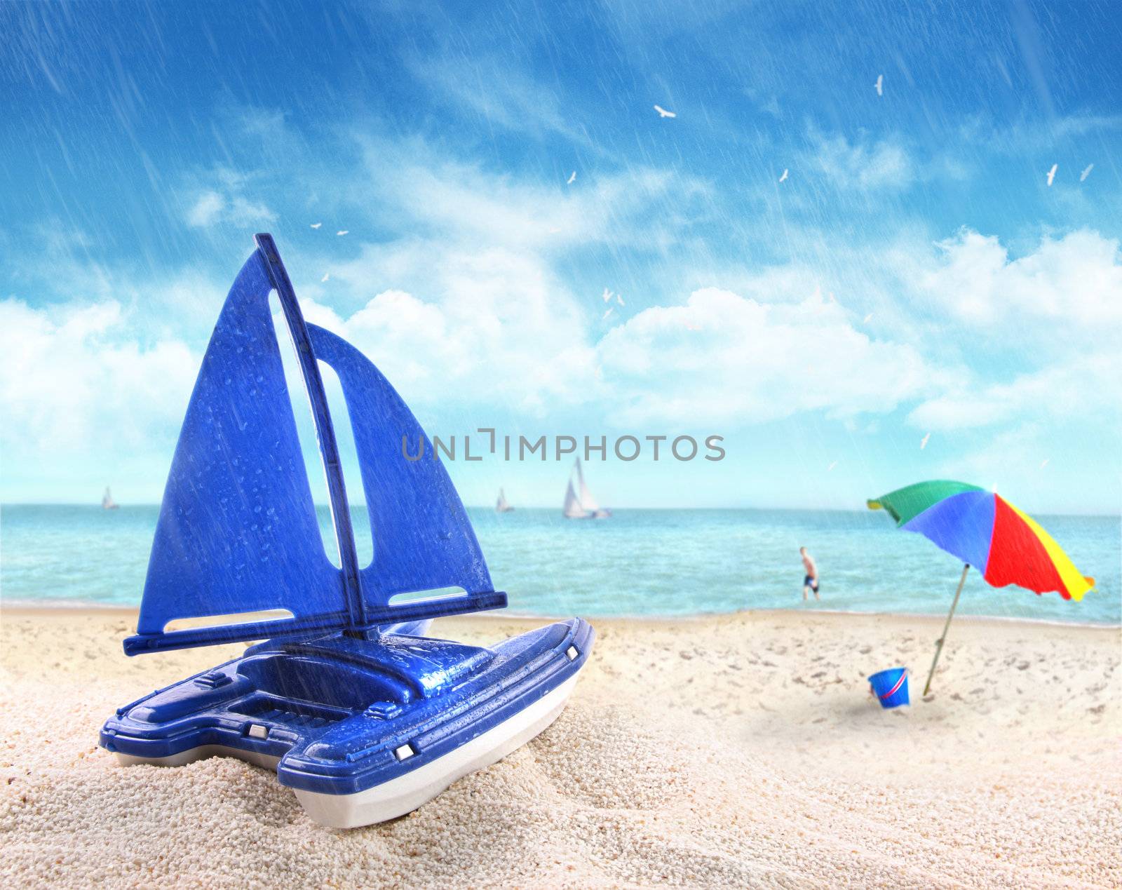 Toy sailboat in sand with beach scene by Sandralise