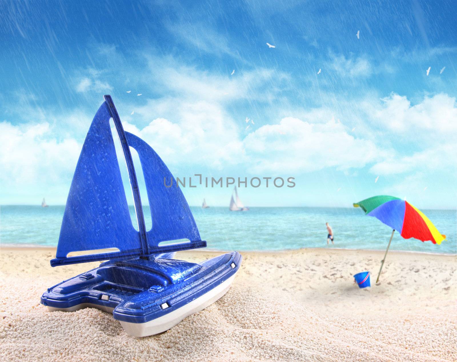 Toy sailboat in sand with beach scene in background