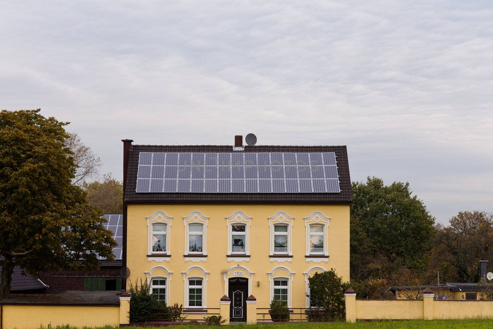Historic house built 1900 has roof covered with modern solar panels for generating green power.