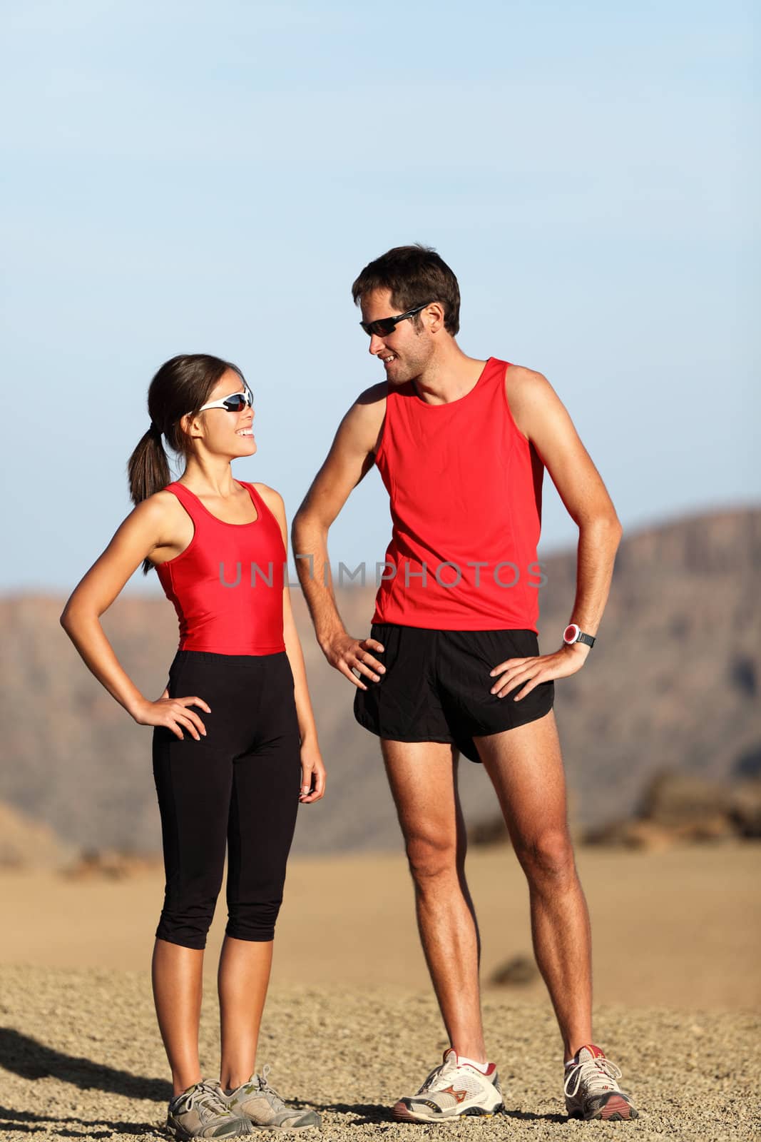 Runner couple in nature taking a break after running in desert mountain landscape.