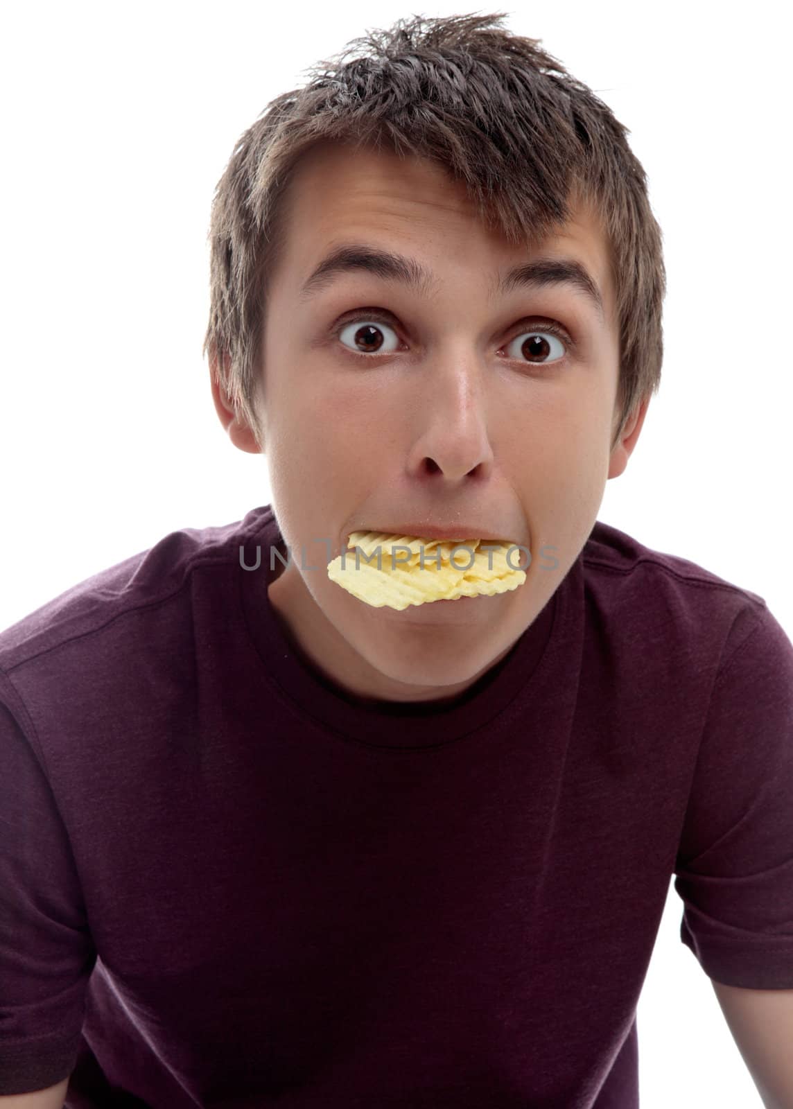 A boy with a mouthful of crinkle cut potato chips.