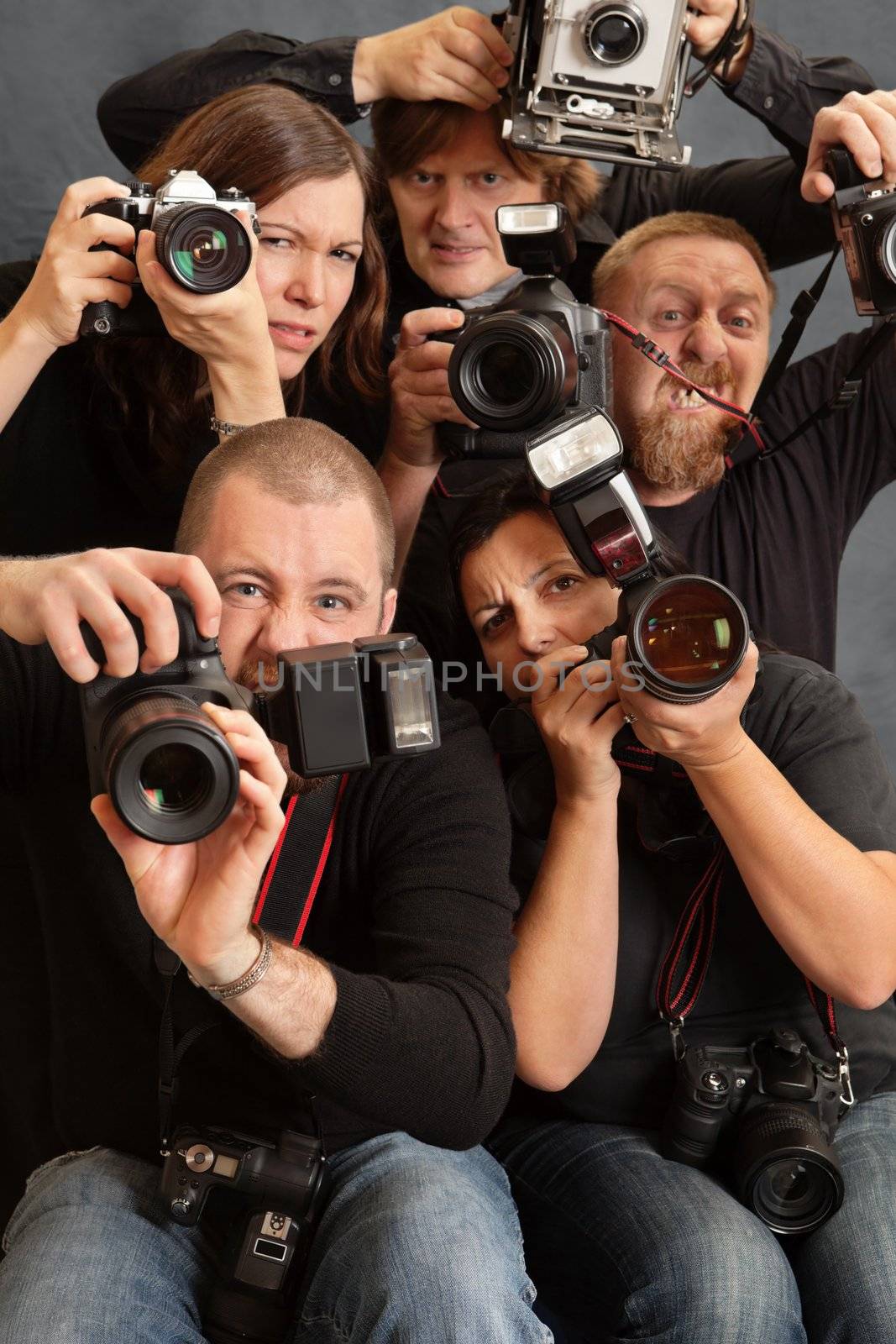 Photo of paparazzi fighting for space to take photos. Focus is on the face of the male in front.