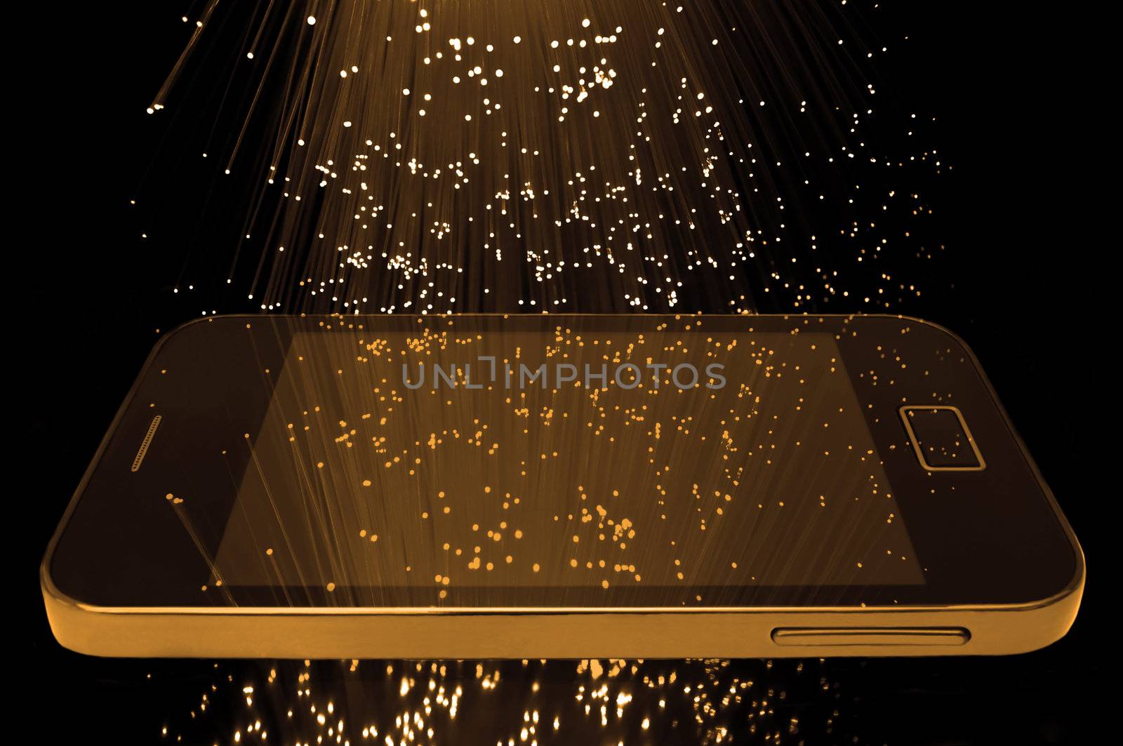 Many illuminated golden fiber optic light strands cascading down against a black background and reflecting on the screen of a smart phone in the foreground