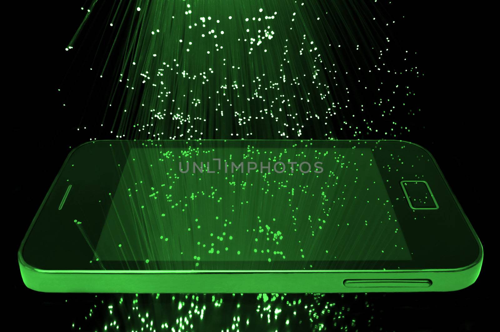 Many illuminated green fiber optic light strands cascading down against a black background and reflecting on the screen of a smart phone in the foreground