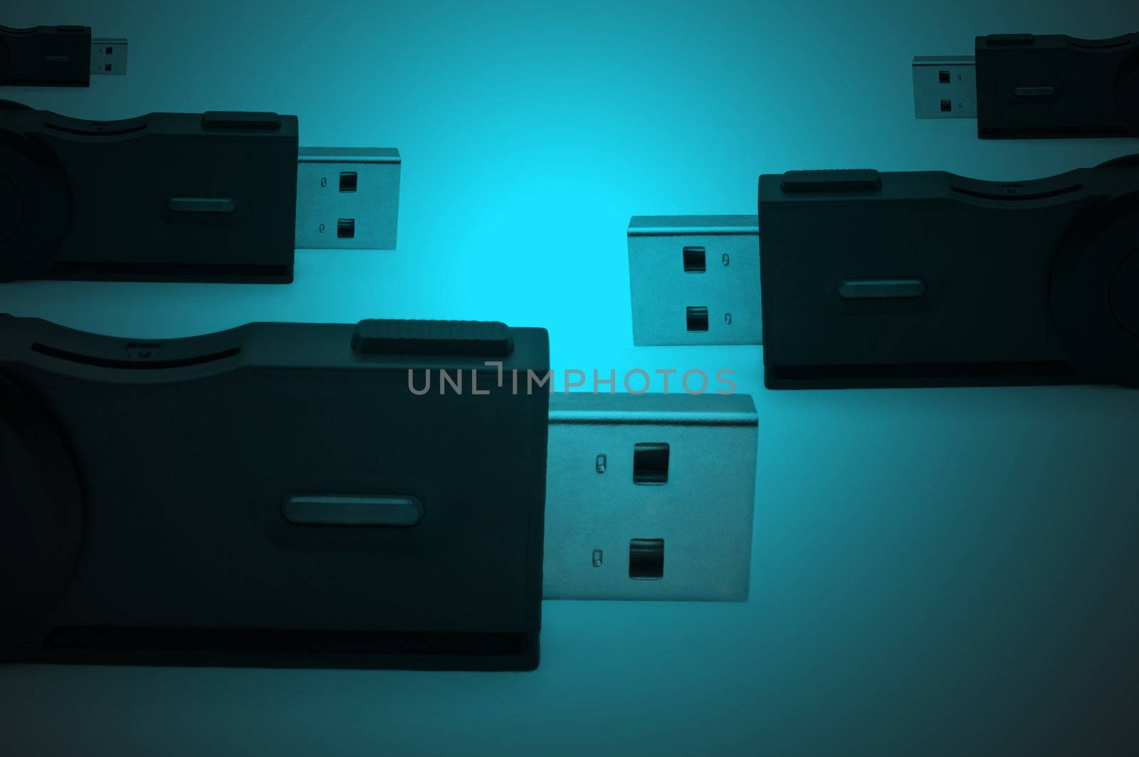 Close and low level capturing portions of several black usb sd adaptors arranged over dark blue light effect