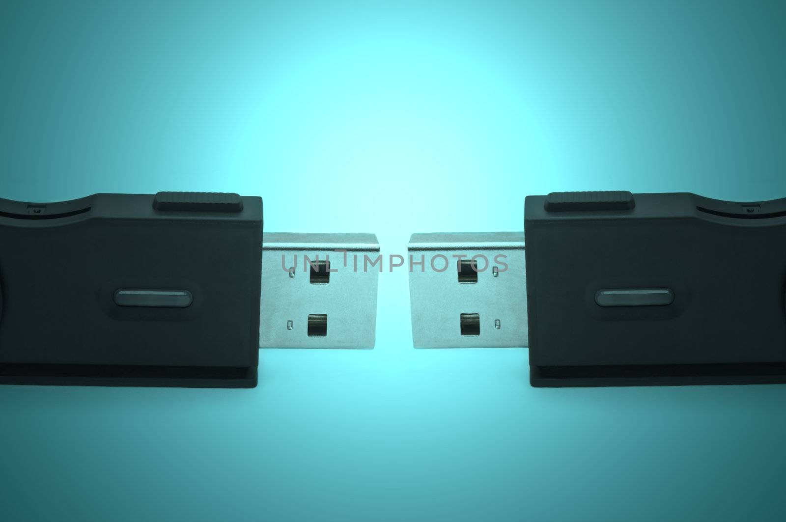 Close and low level capturing two black sd usb adaptors arranged over a blue light effect filter
