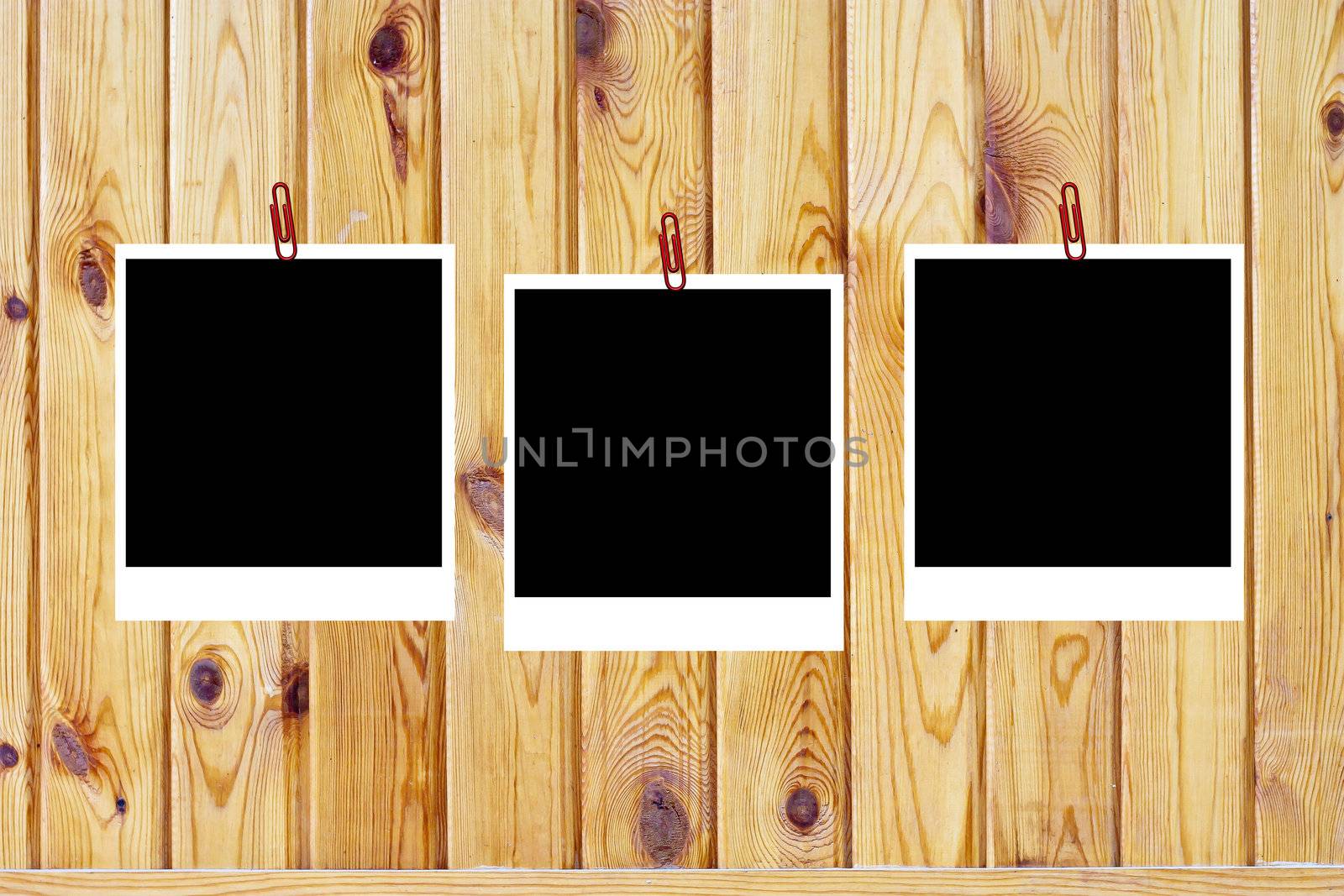 set of three old blank polaroids frames lying on a wood surface 