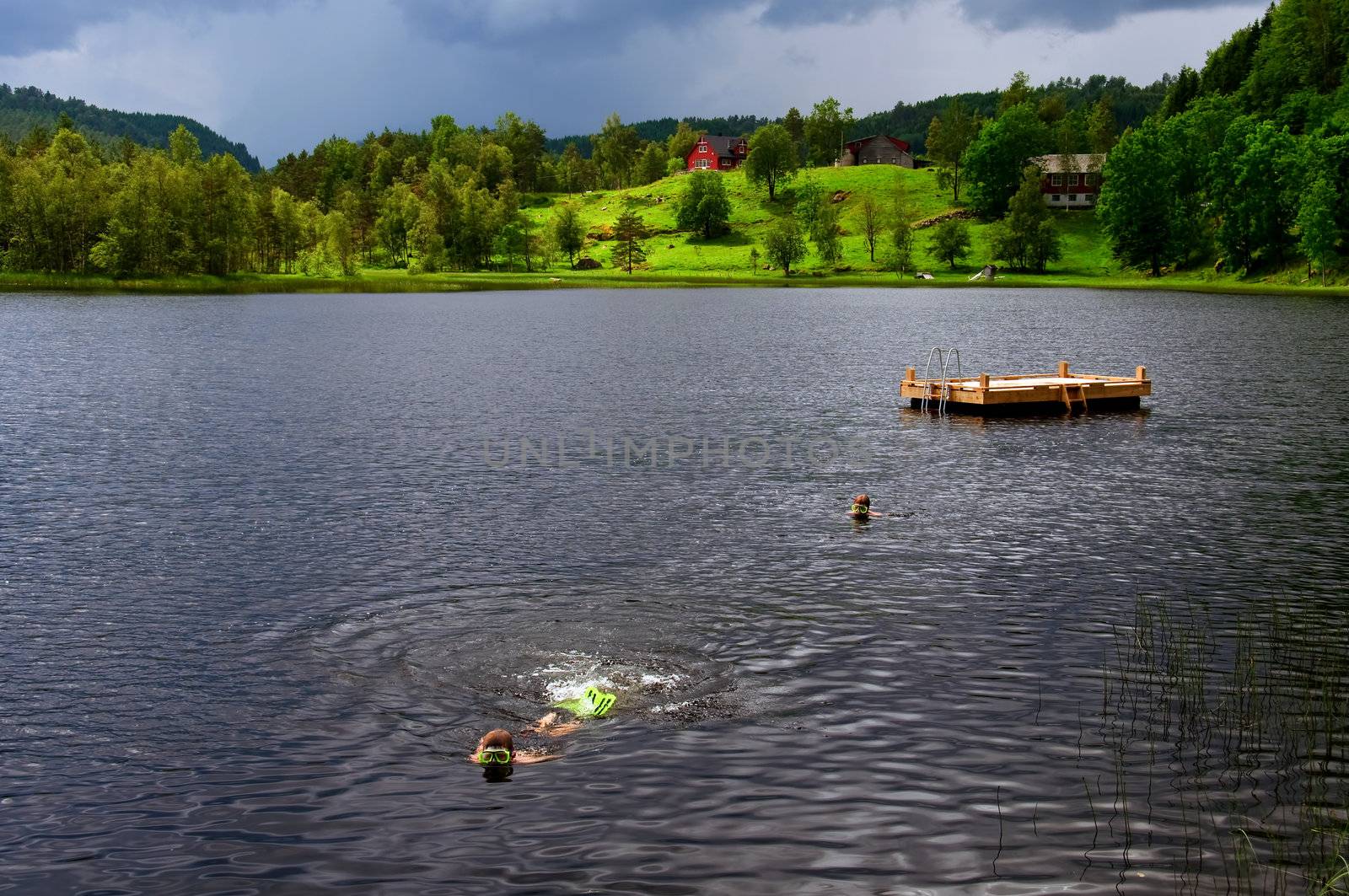 Two children swimming in a lake wearing diving masks