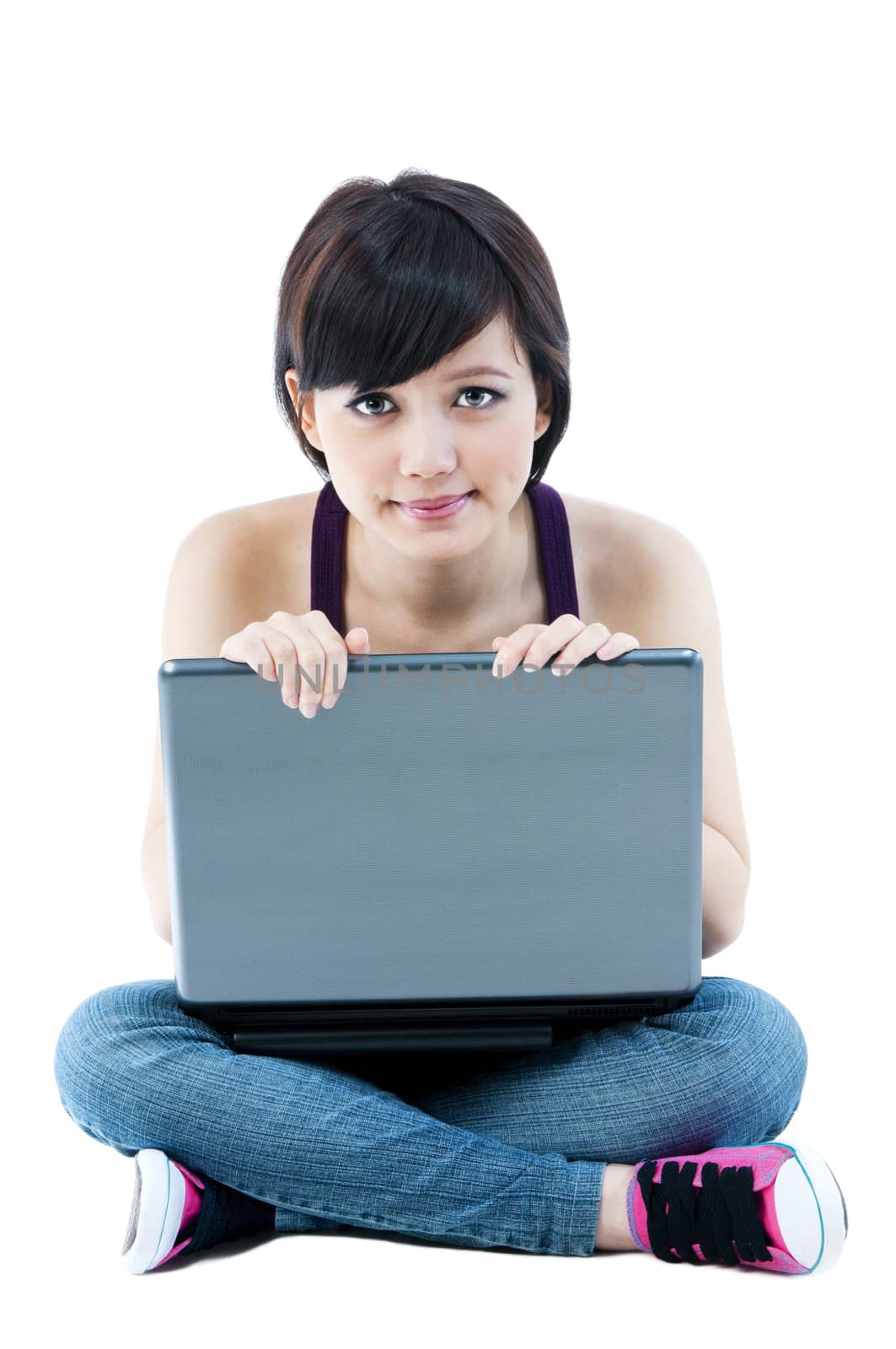 Portrait of a cute young Asian woman sitting on floor with laptop over white background.
