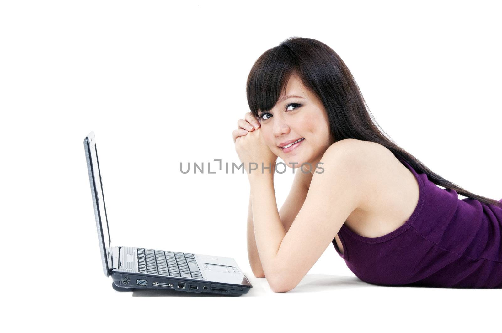 Portrait of an attractive young Asian woman lying on the floor with laptop over white background.