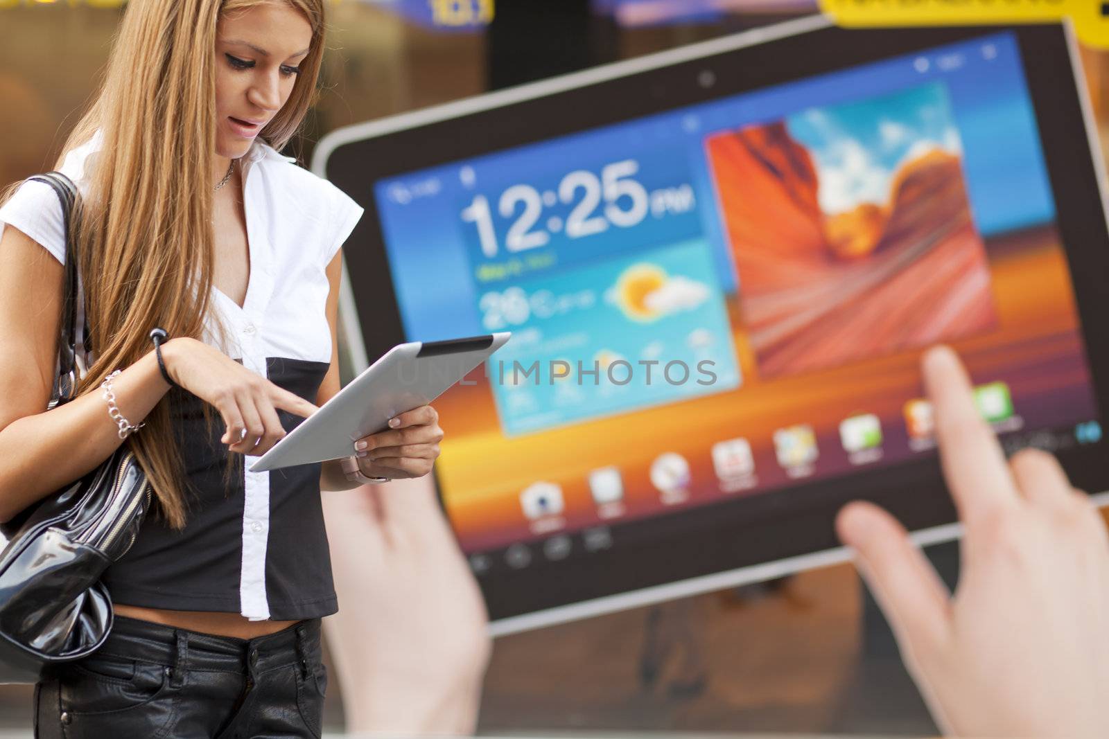 Young Woman with tablet computer walking on street, downtown. In background is blured advertisiment with OpenSource graphics. Visible noise
