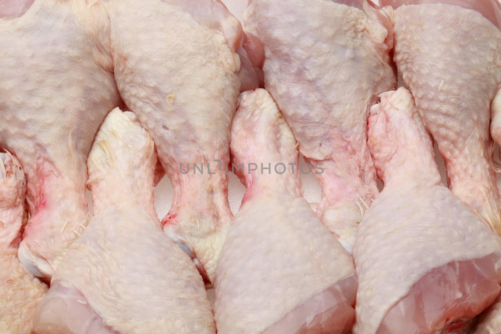 Closeup image of several raw chicken drumsticks as they can be found on the shelfs of supermarkets.