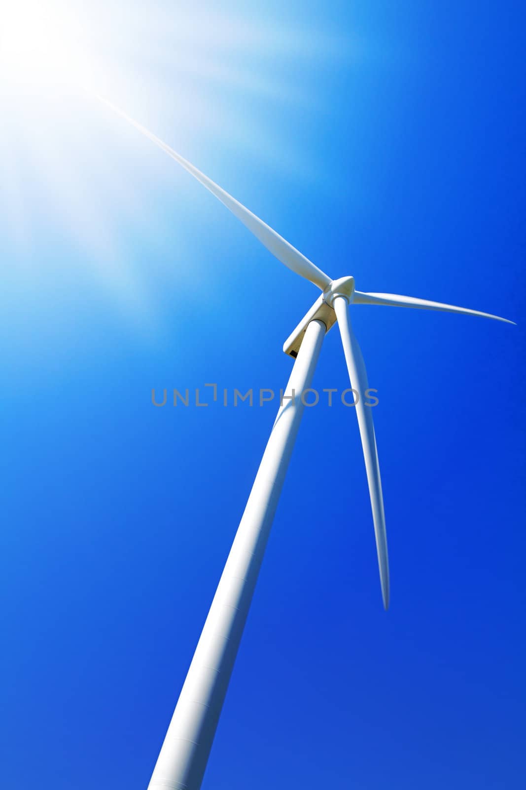 Wind turbine under clear blue sky by chrisroll