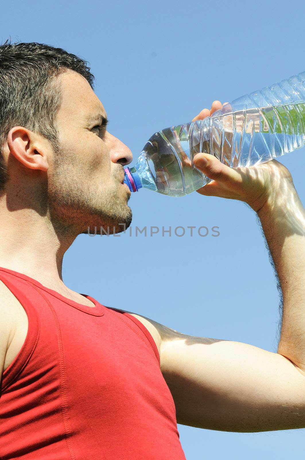 Man is drinking water against blue sky