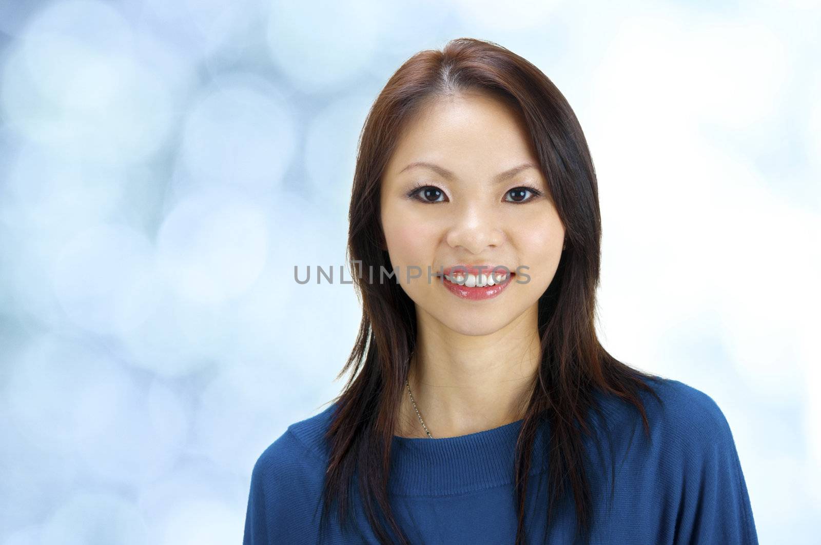Close-up of a beautiful young woman smiling on blue background