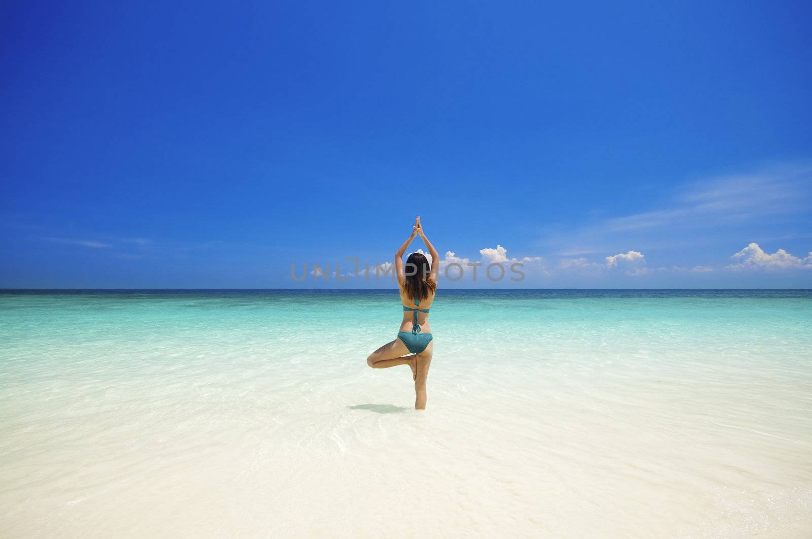 Woman doing yoga (tree pose) on the beach