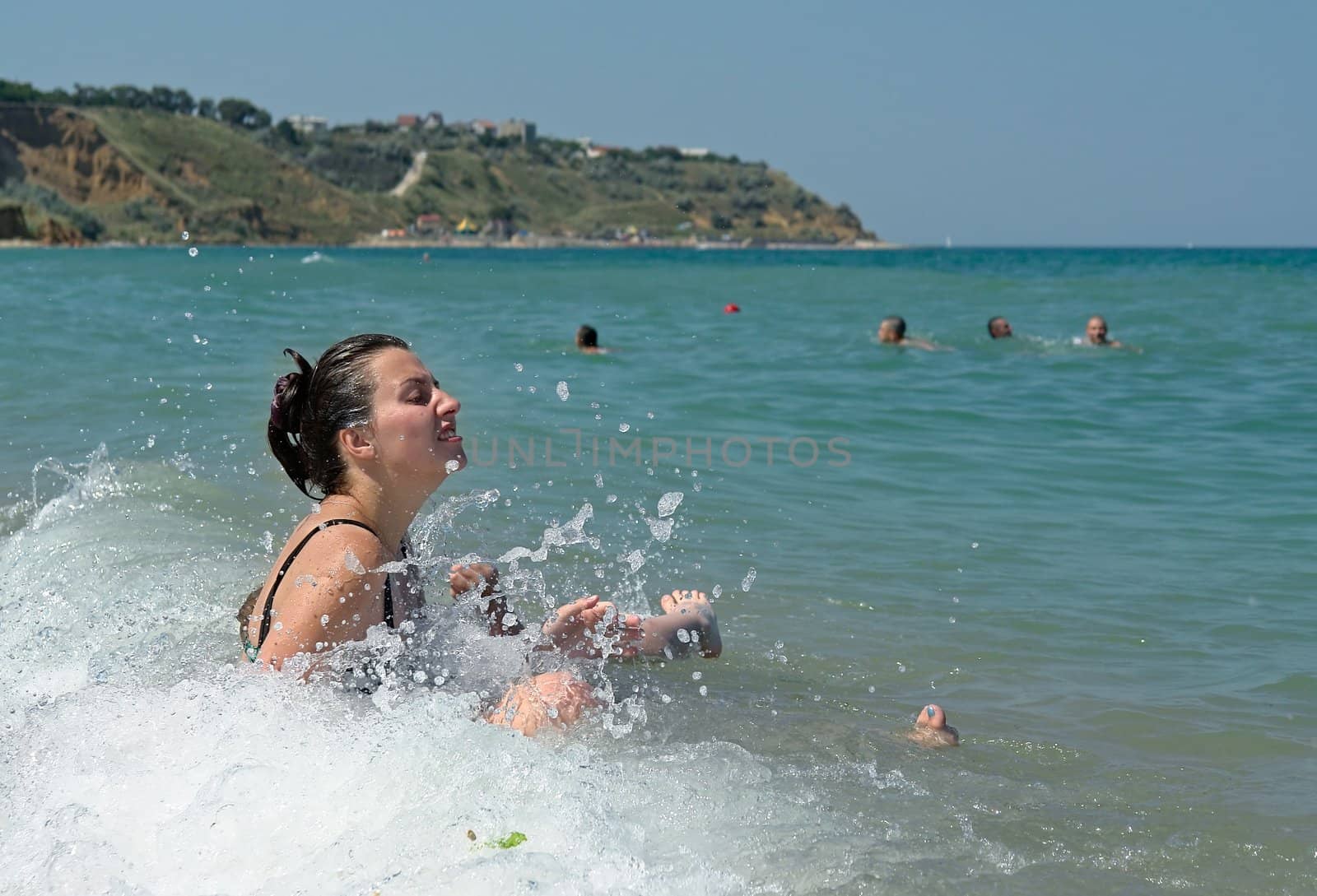 Smilling young woman in sea-foam of ocean