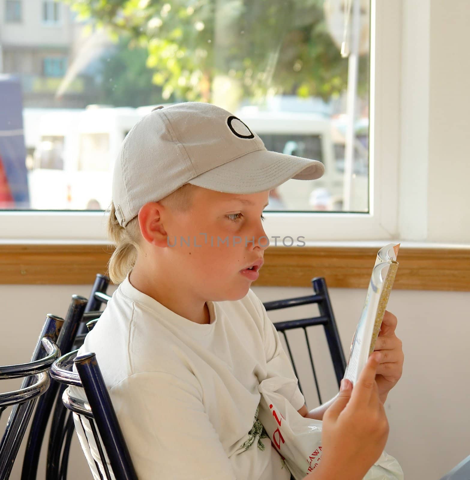 The little boy reads the book in cafe