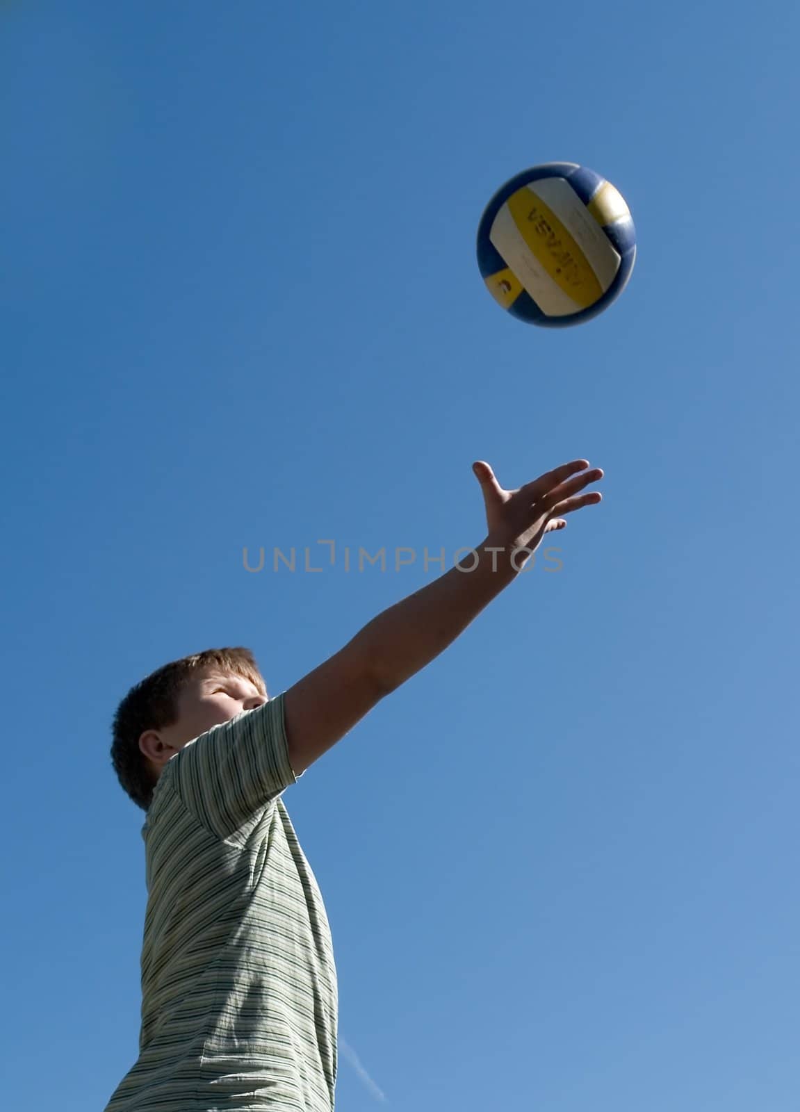 A little boy plays a ball with sky at background 