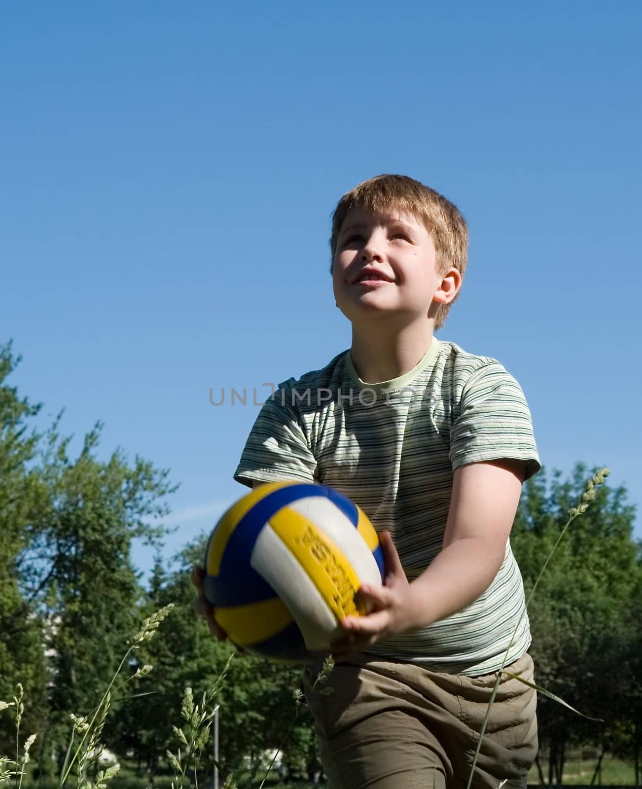 A little boy plays a ball with sky at background