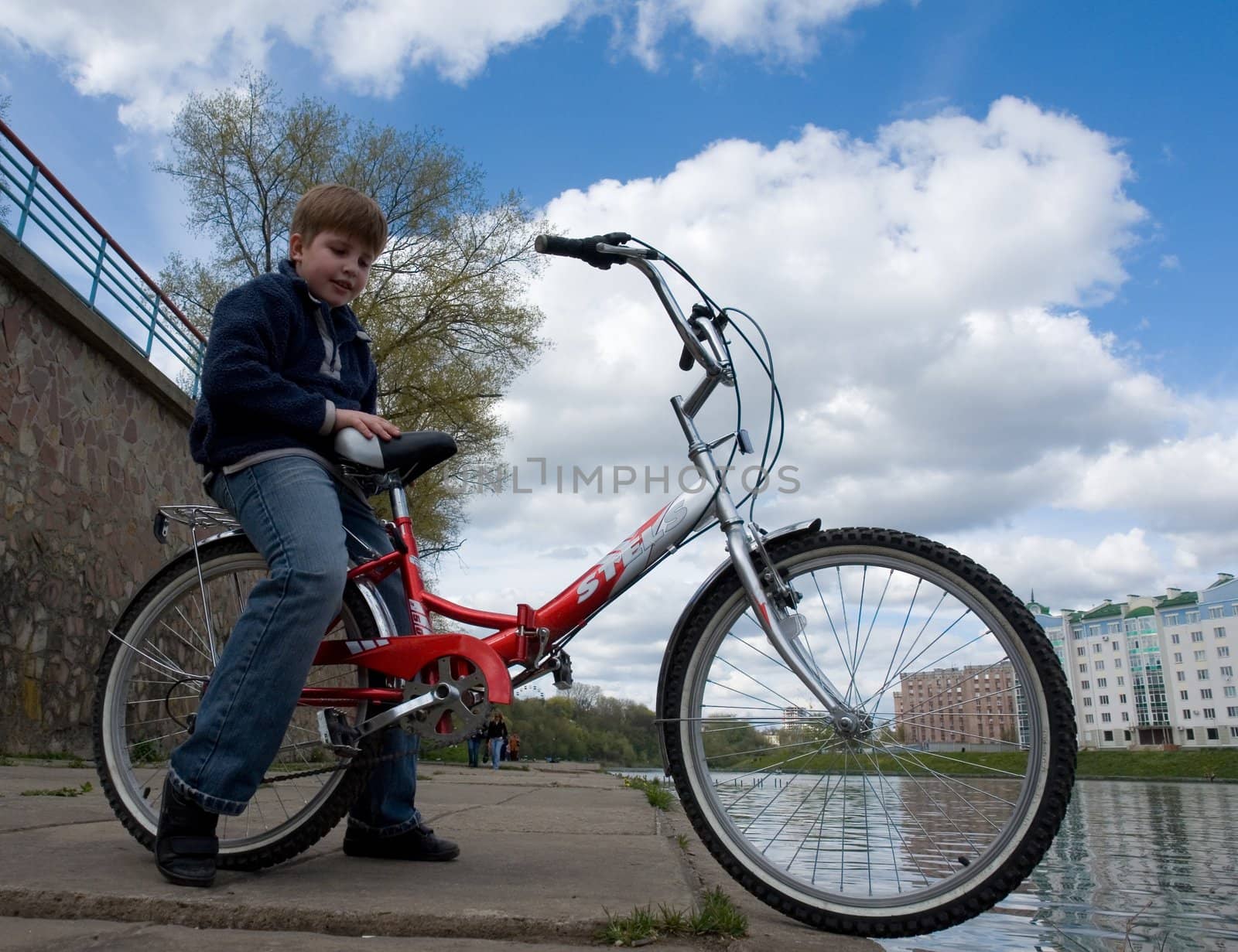 Boy on a bicycle with cloudy sky at background