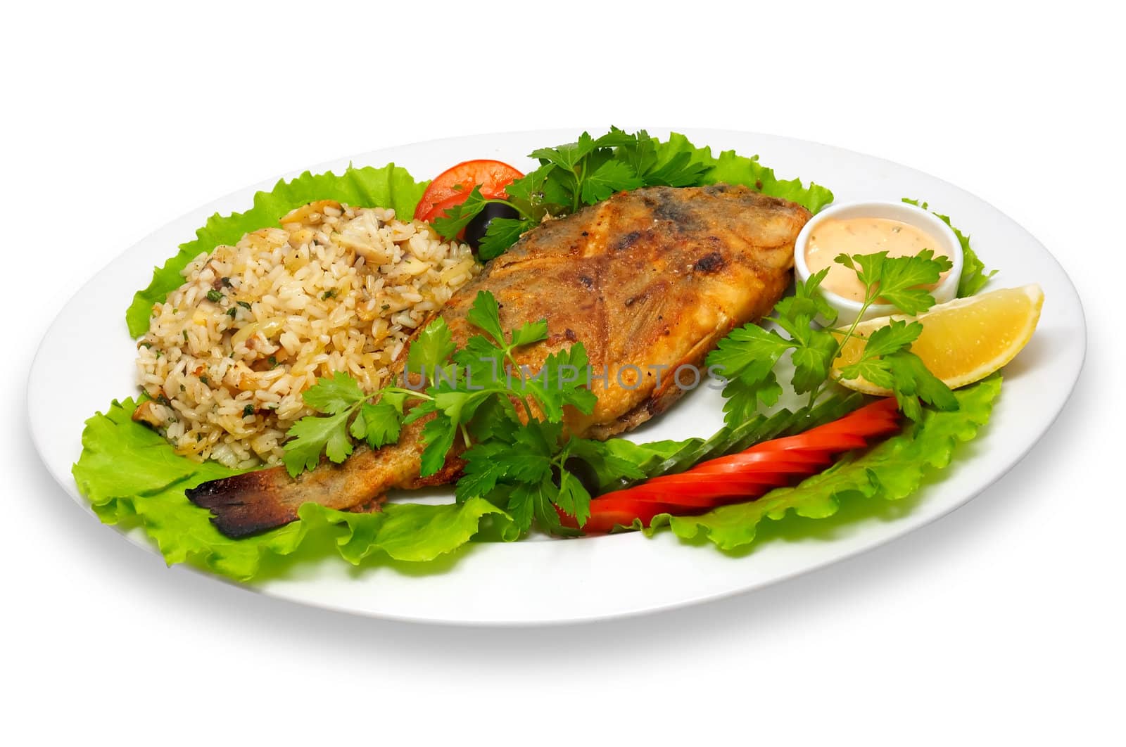 whole grilled rock-fish, with rice and fresh tomatoes, lays on lettuce leaves with lemon slice.