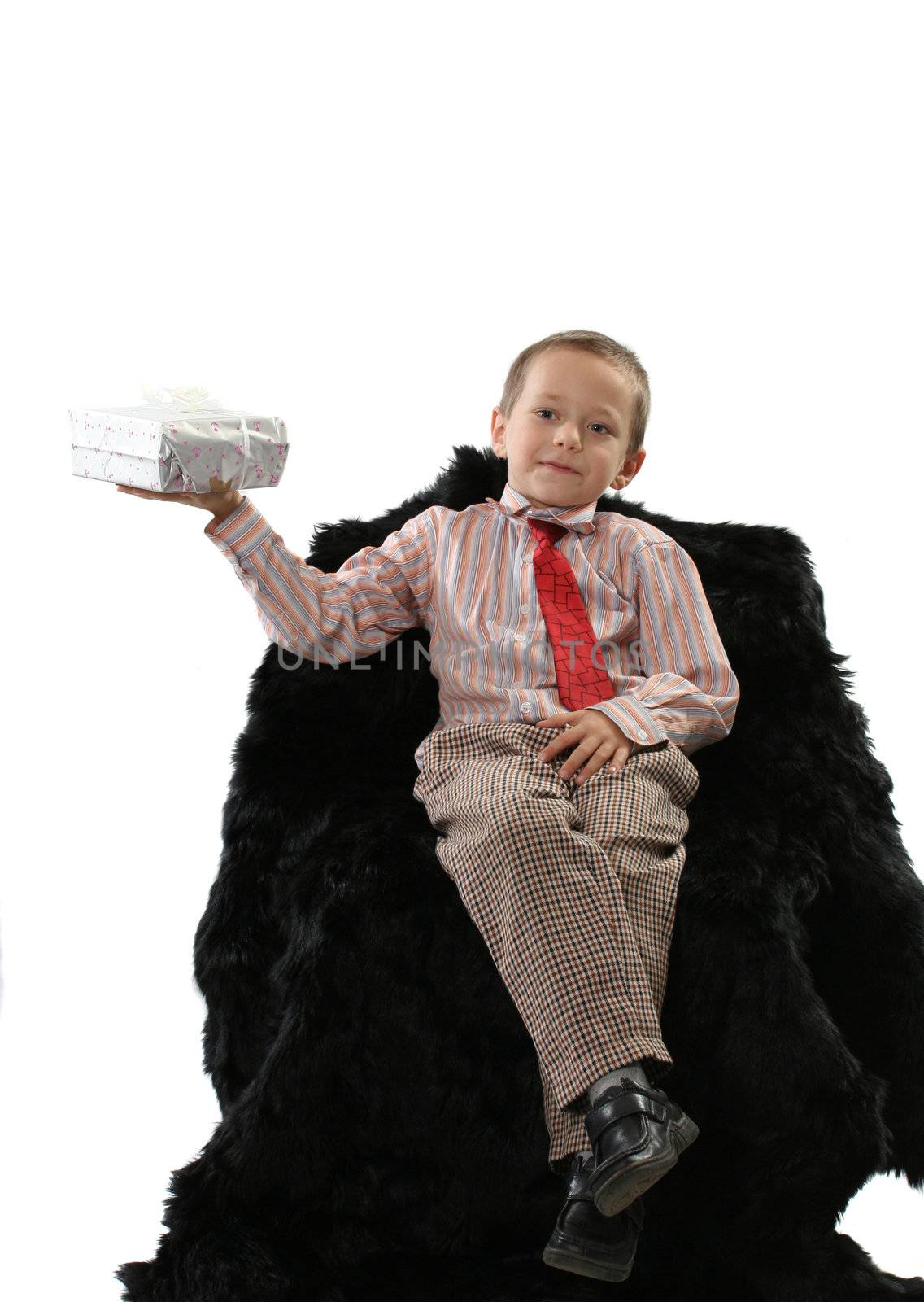 The boy sits in an armchair and holds a gift