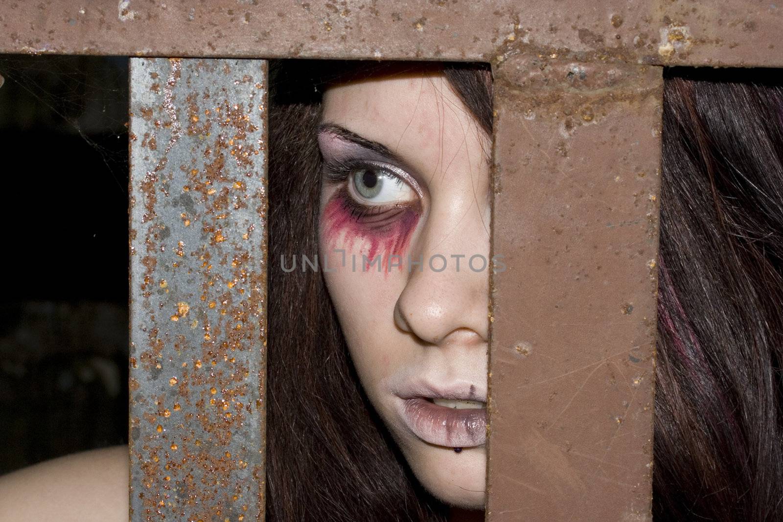 The girl-vampire behind an iron rusty lattice