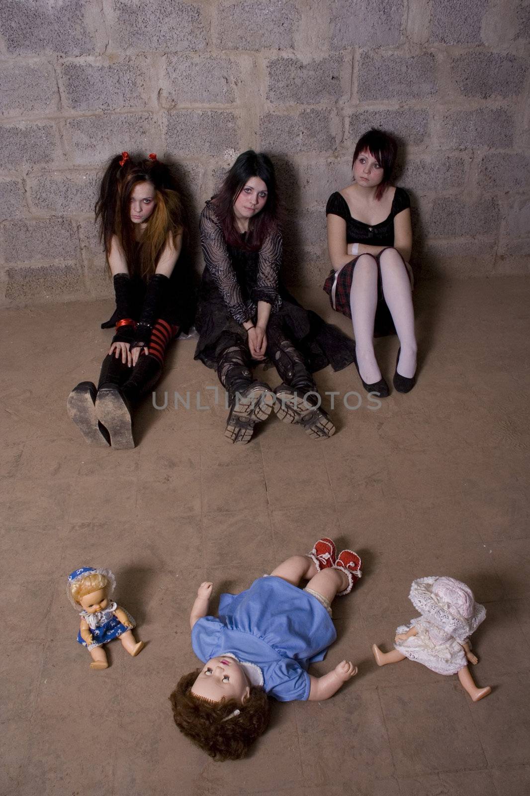 Girls with dolls sit on a floor in depression