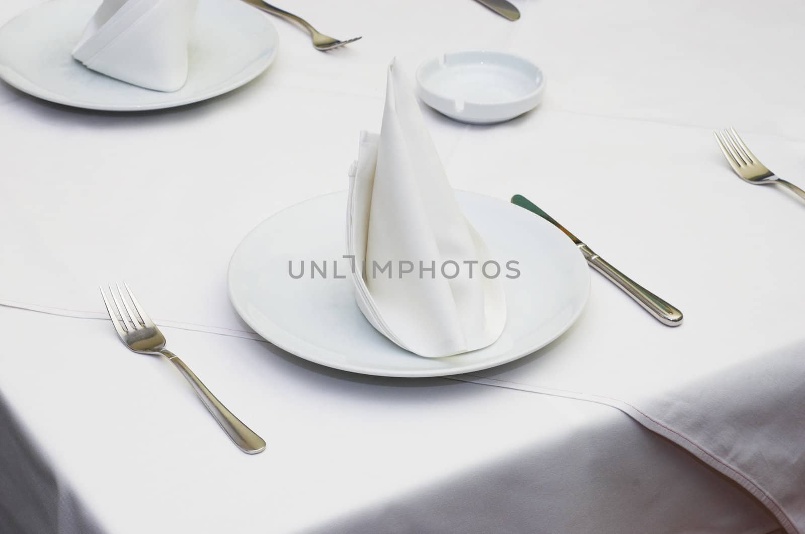 Empty served restaurant table with white tablecloth