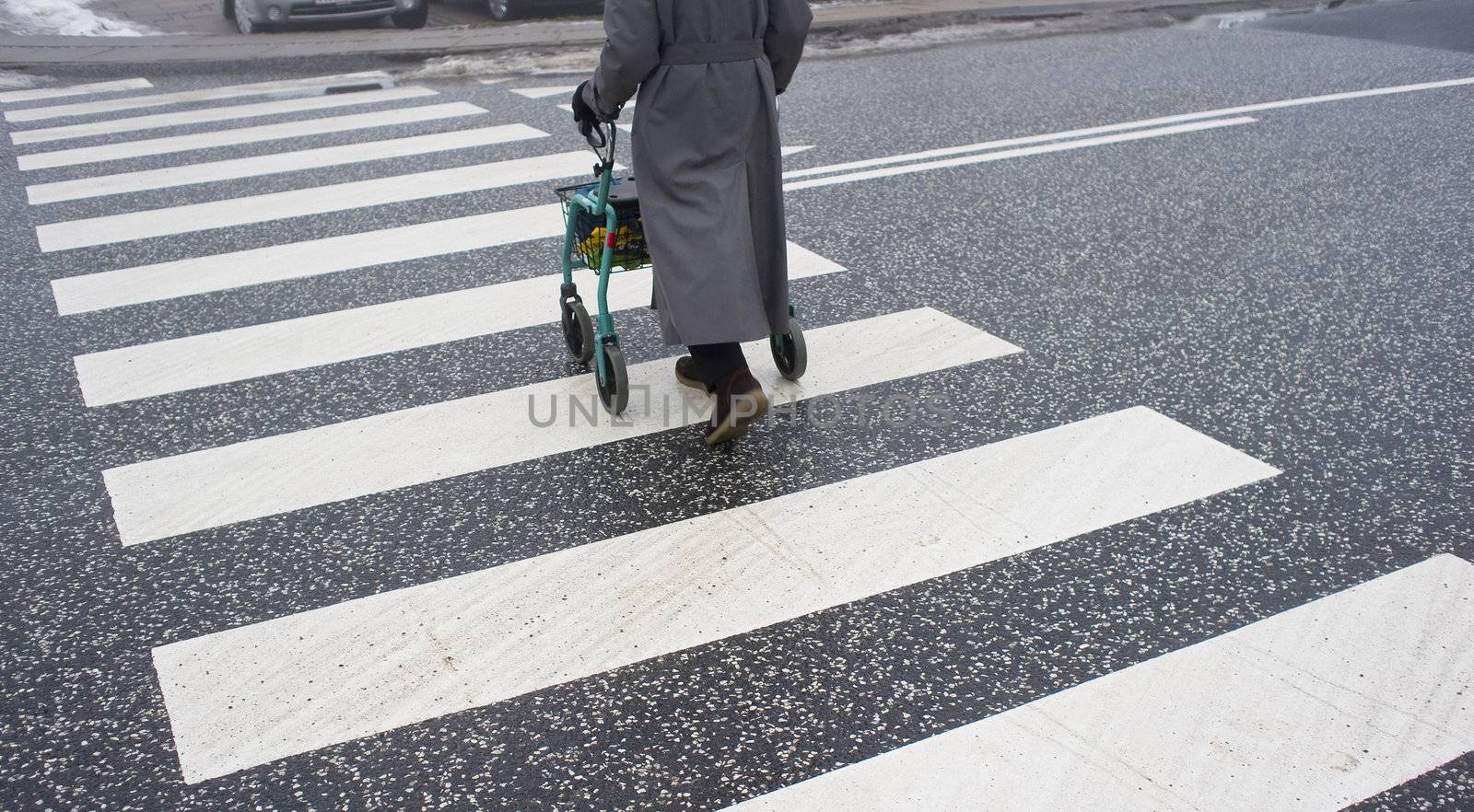 Disabled elderly female with her walker in a zebra crossing - Denmark at wintertime.